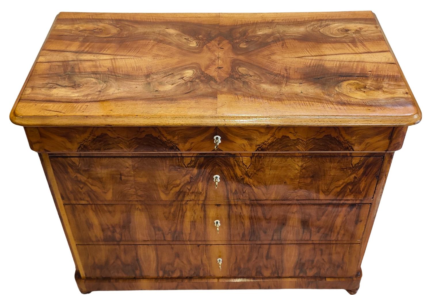 Questa raffinata cassettiera Biedermeier è stata realizzata nel sud della Germania intorno al 1830 e si distingue per l'impiallacciatura di noce riccamente figurata con una bellissima venatura a libro. Il frontale presenta quattro cassetti con