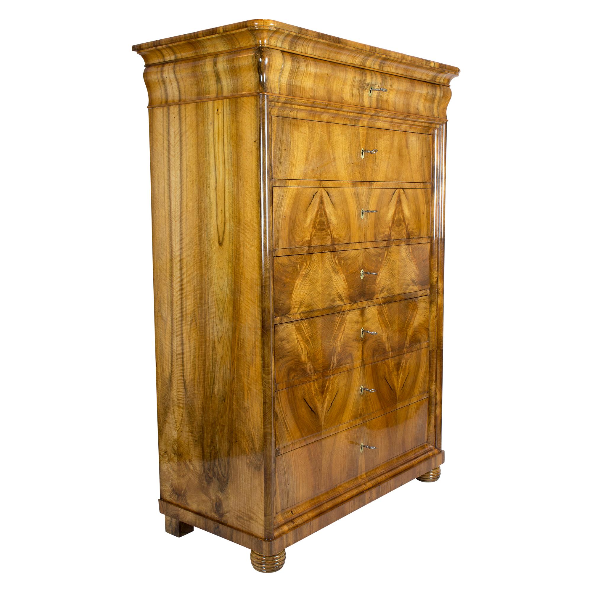 The chiffoniere comes from Southern Germany from the Biedermeier period around 1830. The seven drawers of the high chest can all be closed individually. The chiffoniere has a very beautiful mirrored walnut veneer. The key plates are made of brass