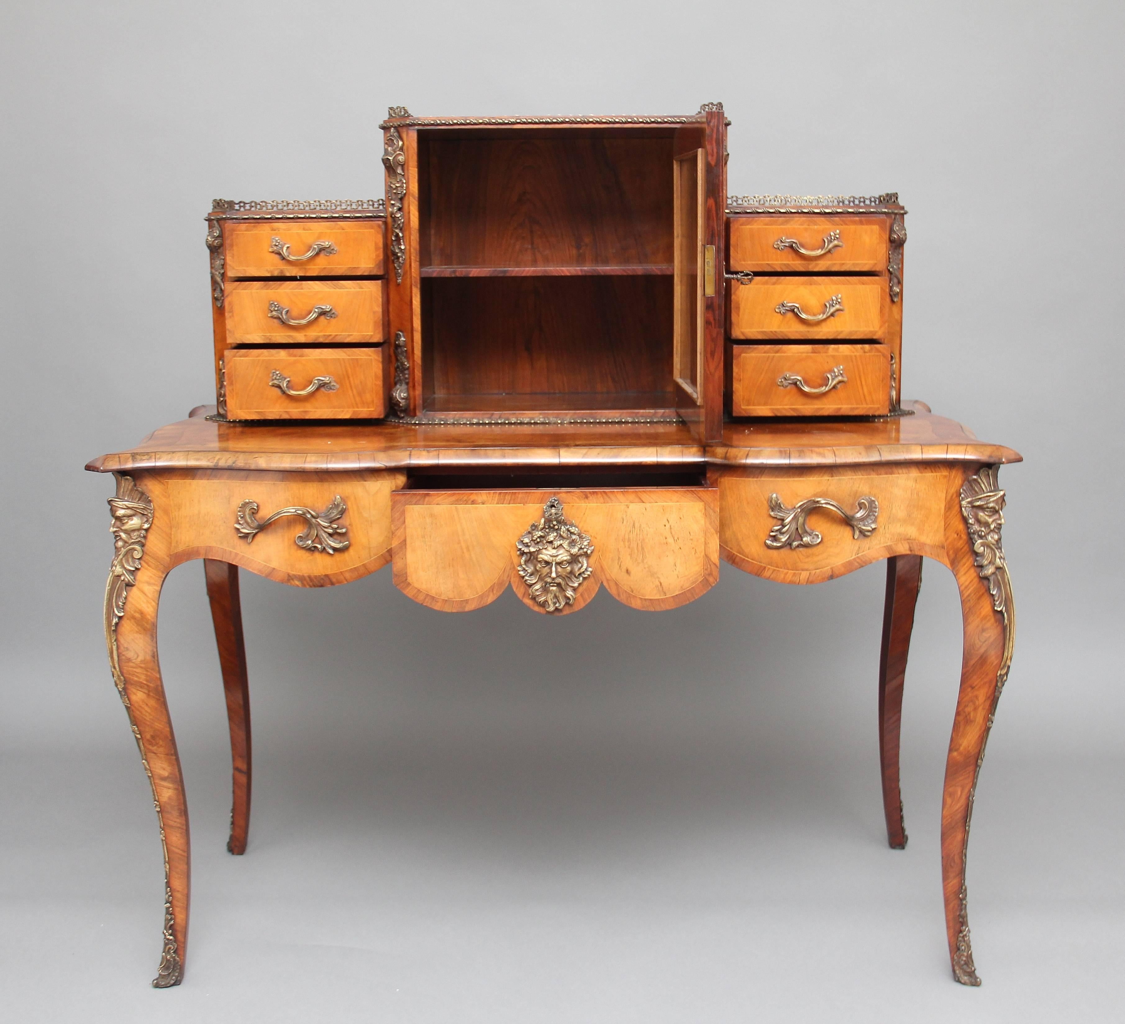 A superb quality 19th century walnut inlaid and gilt metal mounted desk or Bonheur Du Jour of lovely color and proportions, the top having a brass gallery running along all three sections, a cupboard at the centre with a single fixed shelf inside,