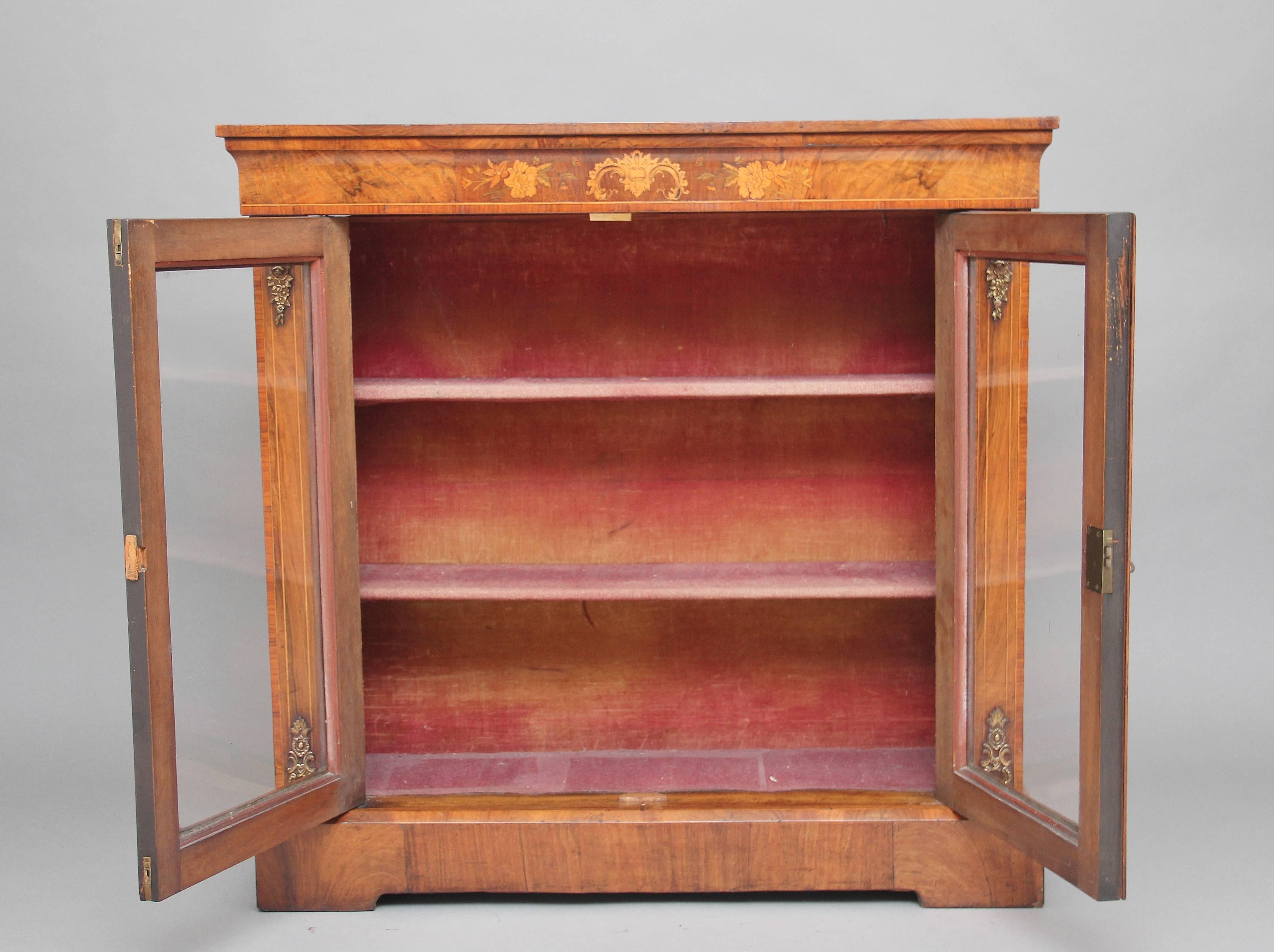 19th century walnut pier cabinet or bookcase, the rectangular top above a frieze which is wonderfully inlaid with floral decoration, above a pair of glazed doors with the door frames inlaid with boxwood lines, opening to reveal two fixed shelves