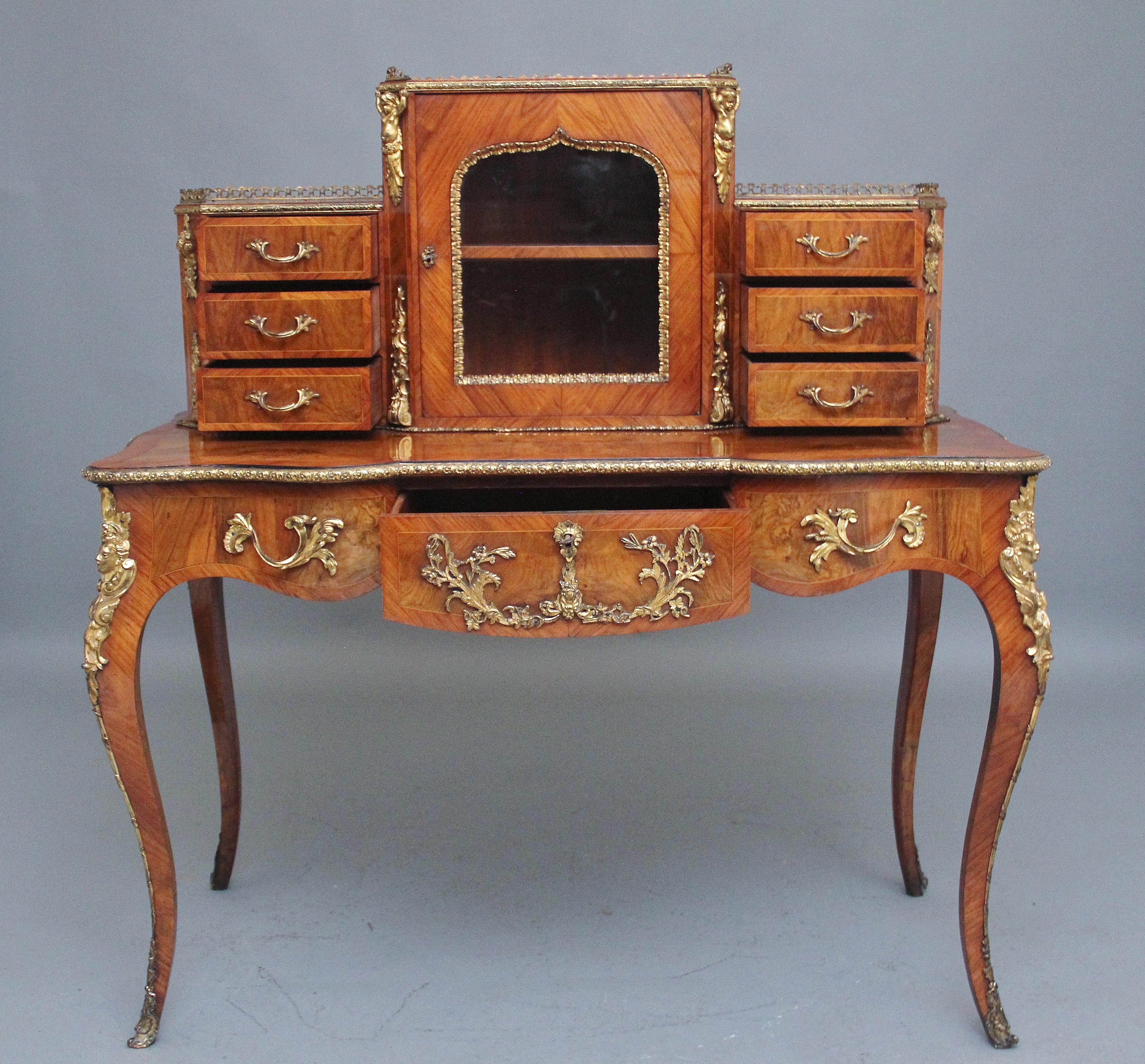 An exhibition quality 19th Century walnut Bonheur Du Jour / desk by Gillows, the top having a brass gallery running along all three sections, a cupboard at the centre with a glazed door opening to reveal a single shelf inside, lovely ormolu beading