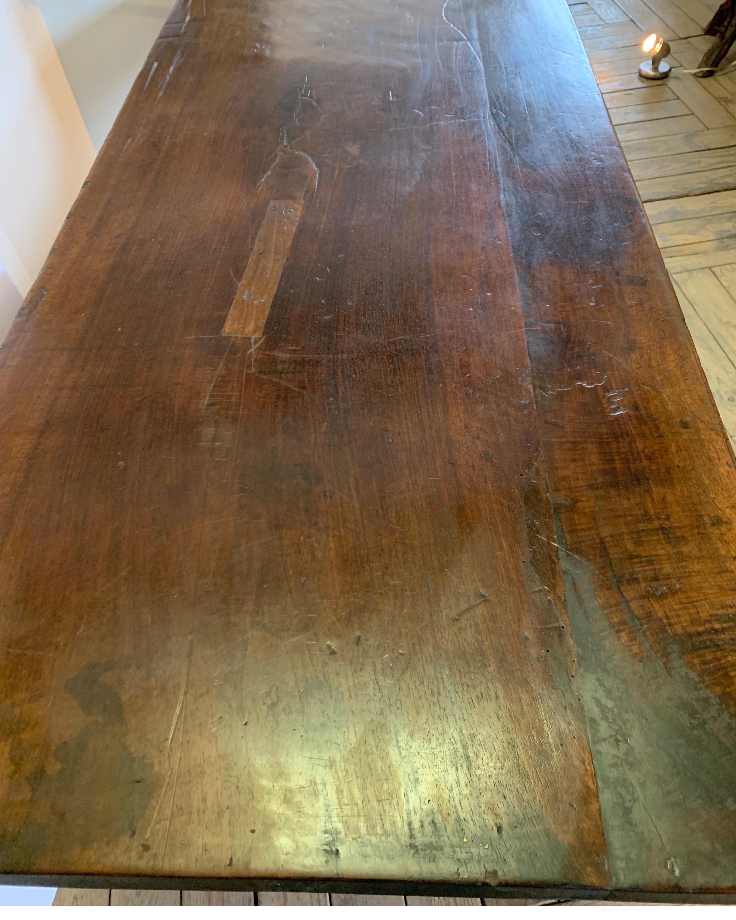 This handsome walnut table is a handsome very sturdy dining table. It has great character with several hand done repairs to the top which I have photographed for you to see up close. The color is a dark walnut and much prettier in person.