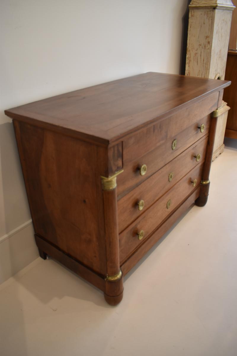 Descubre la elegancia y la grandeza del siglo XIX con esta Cómoda Imperio de Nogal. Es un mueble impresionante que personifica el estilo lujoso y la impecable artesanía del periodo Imperio. Esta exquisita cómoda es un testimonio intemporal del arte