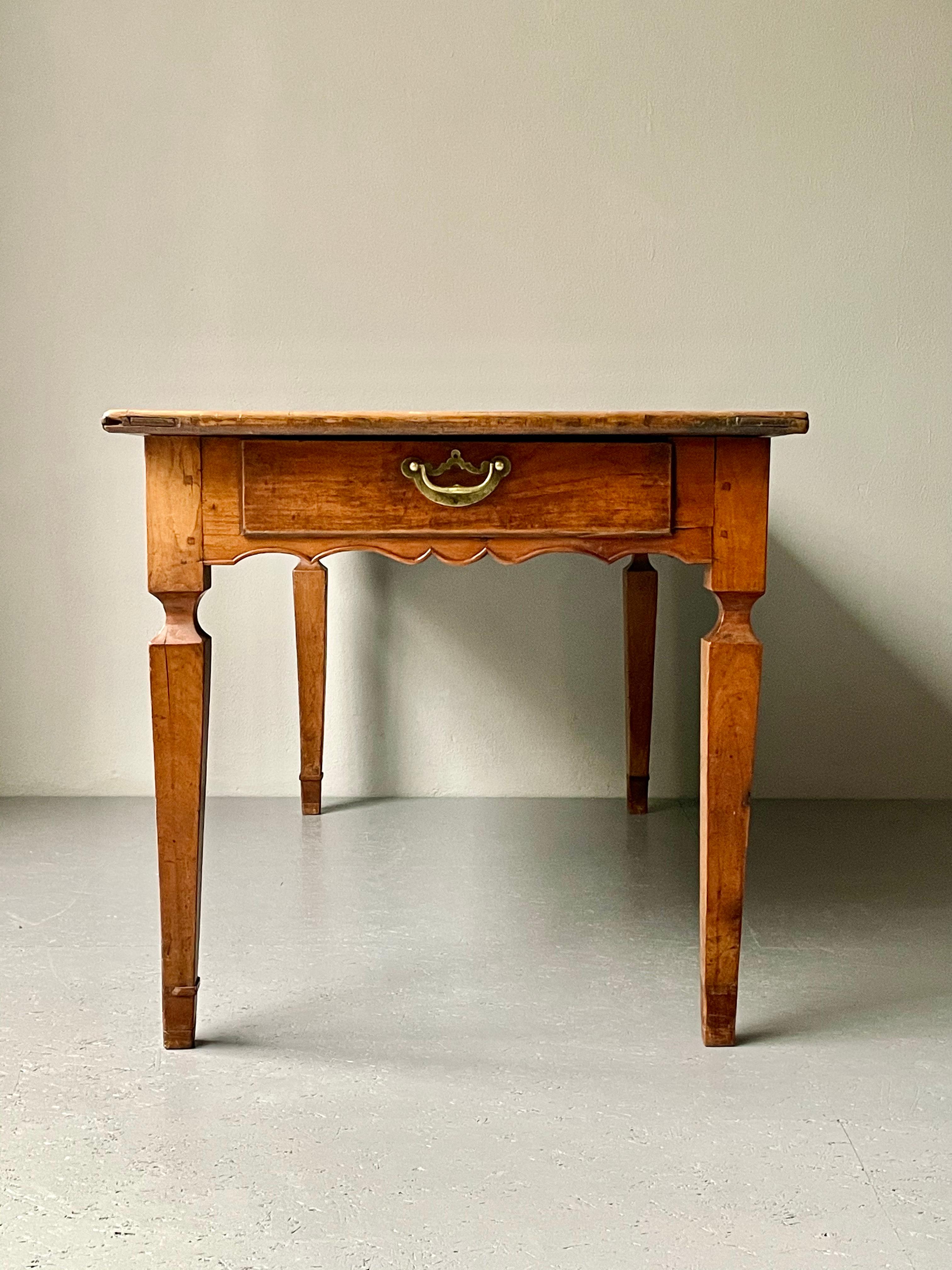 Antique Provençal dining table with tapered legs. This walnut country table is an excellent example of the French culinary tradition. The table has a pull out drawer at the front as well as a slide out tray at the opposite end, enabling for a superb