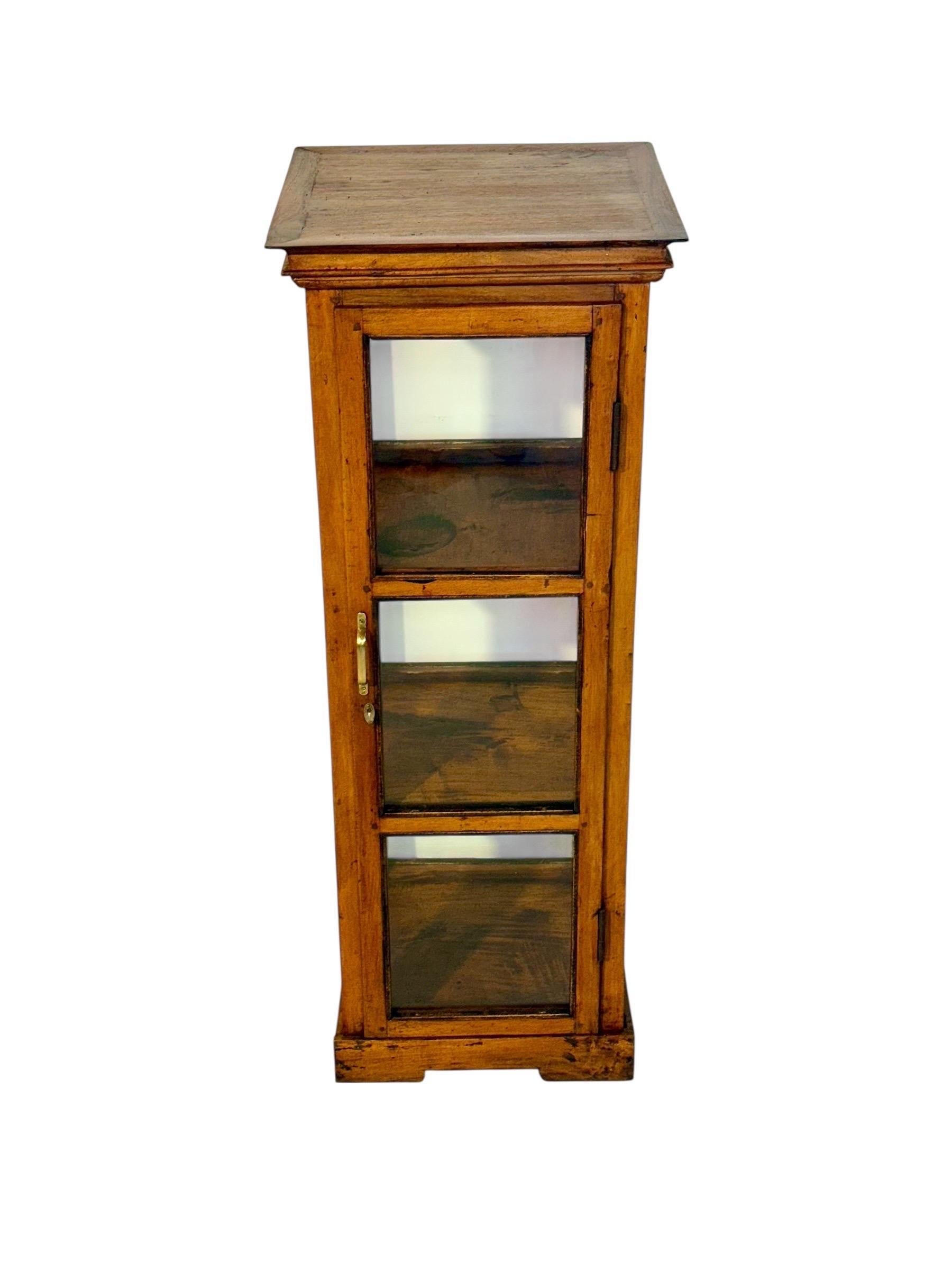 Diese elegante antike Vitrine aus Nussbaumholz mit Glasscheiben an vier Seiten stammt aus dem späten 19. Jahrhundert, etwa aus dem Jahr 1880. Das kompakte und doch raffinierte Möbelstück verfügt über eine einzige Glastür, die in drei Abschnitte