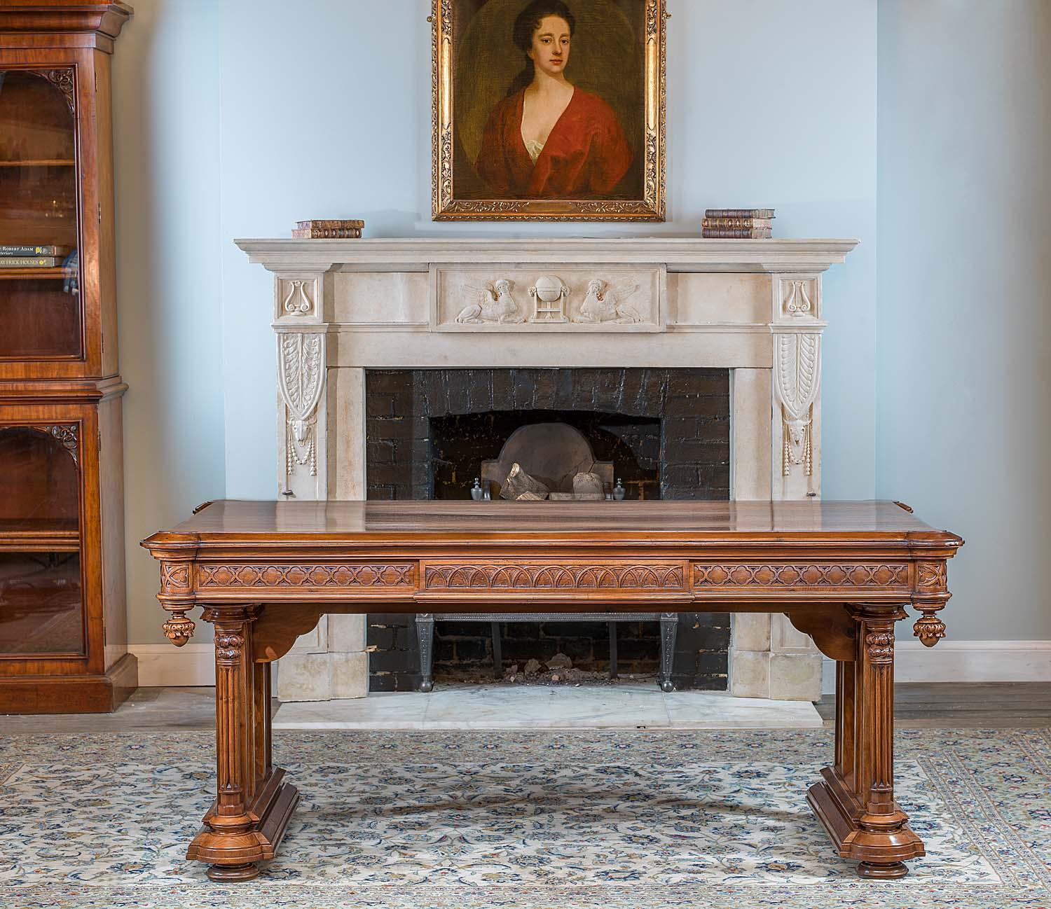 A beautifully carved Gothic Revival walnut centre table. The rectangular top, with podium corners above pendant finials reminiscent of Gothic ceiling bosses, sits above a carved, linked quatrefoil frieze with central panels of blind fret interlaced