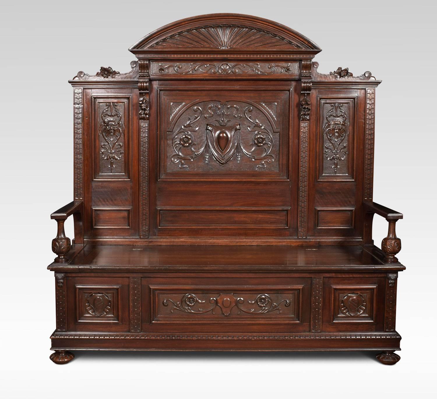 19th century hall settle, the carved walnut panelled high back with an arched and dentil carved cornice. To the seat with lift up lid flanked by moulded arms on leaf carved vase-shaped front pillars. The base with three carved frieze panels all