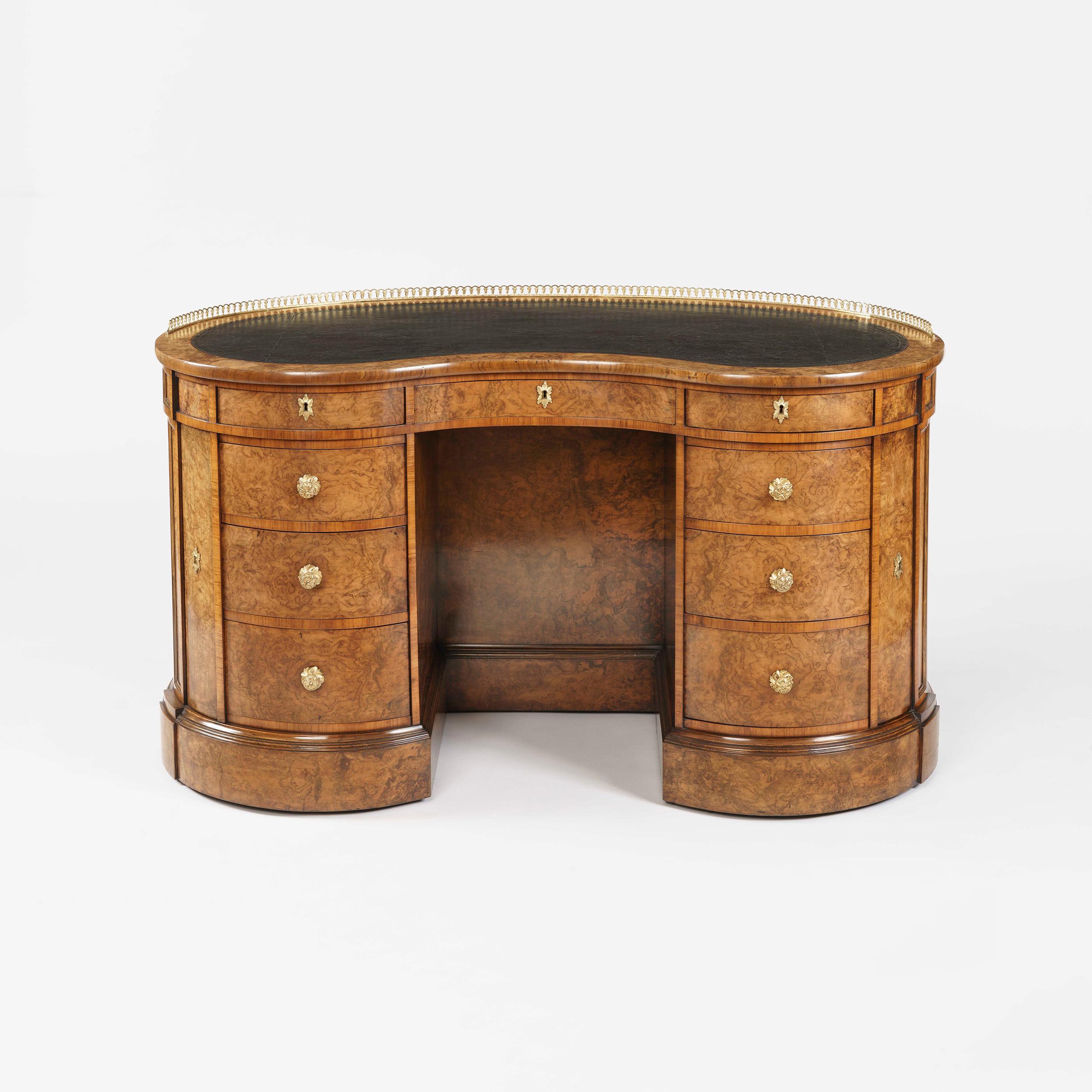 A very fine kidney desk firmly attributed to Gillows.

Constructed in a well-figured walnut and noteworthy amboyna veneers, dressed with splendid bronze handles and escutcheons; of kidney form, an ogee shaped plinth, having an arrangement of nine