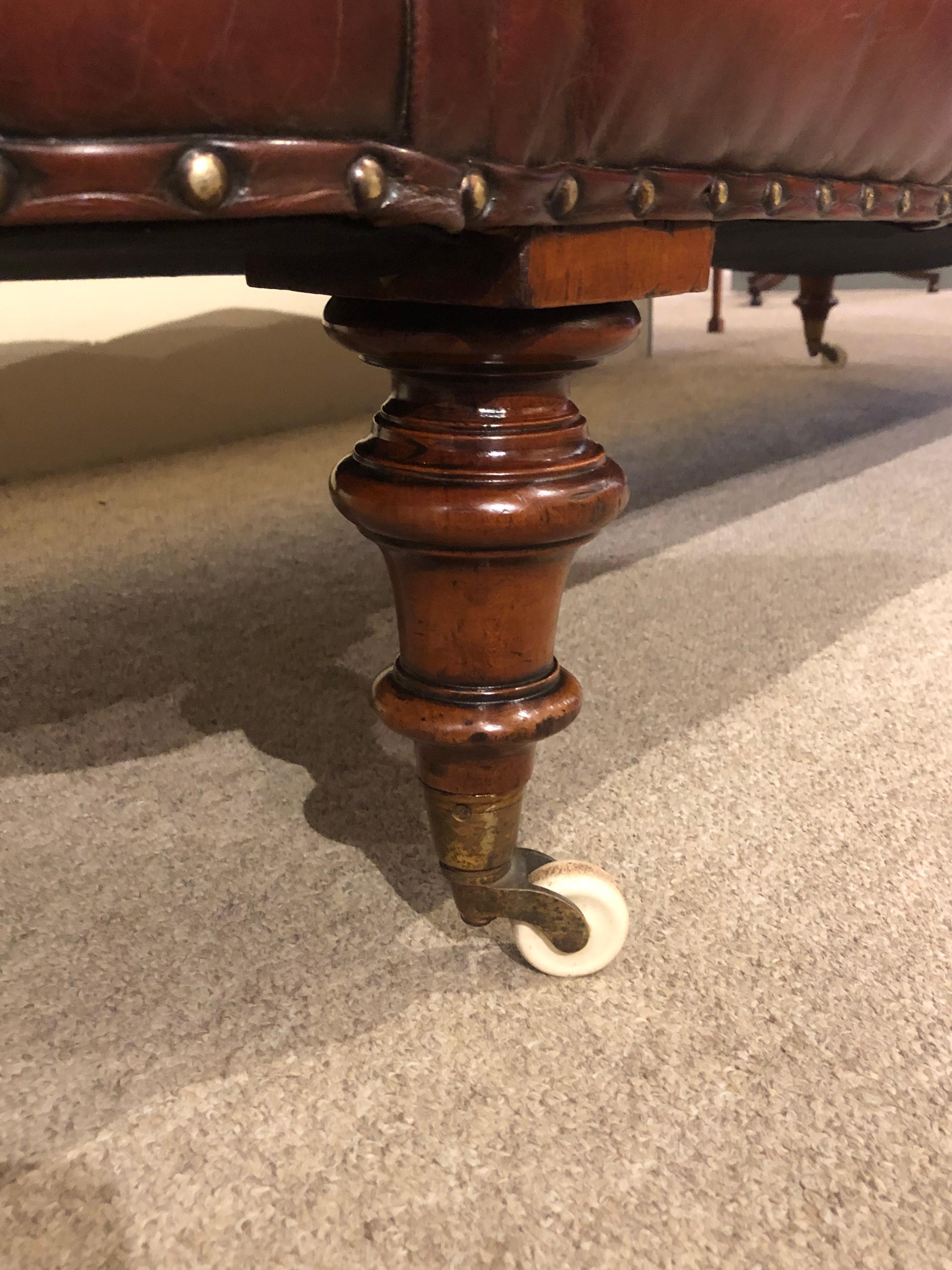 Stunning quality mid-19th century chaise reupholstered in antiqued chestnut leather by master craftsmen, deep buttoned and decorated with brass studs.