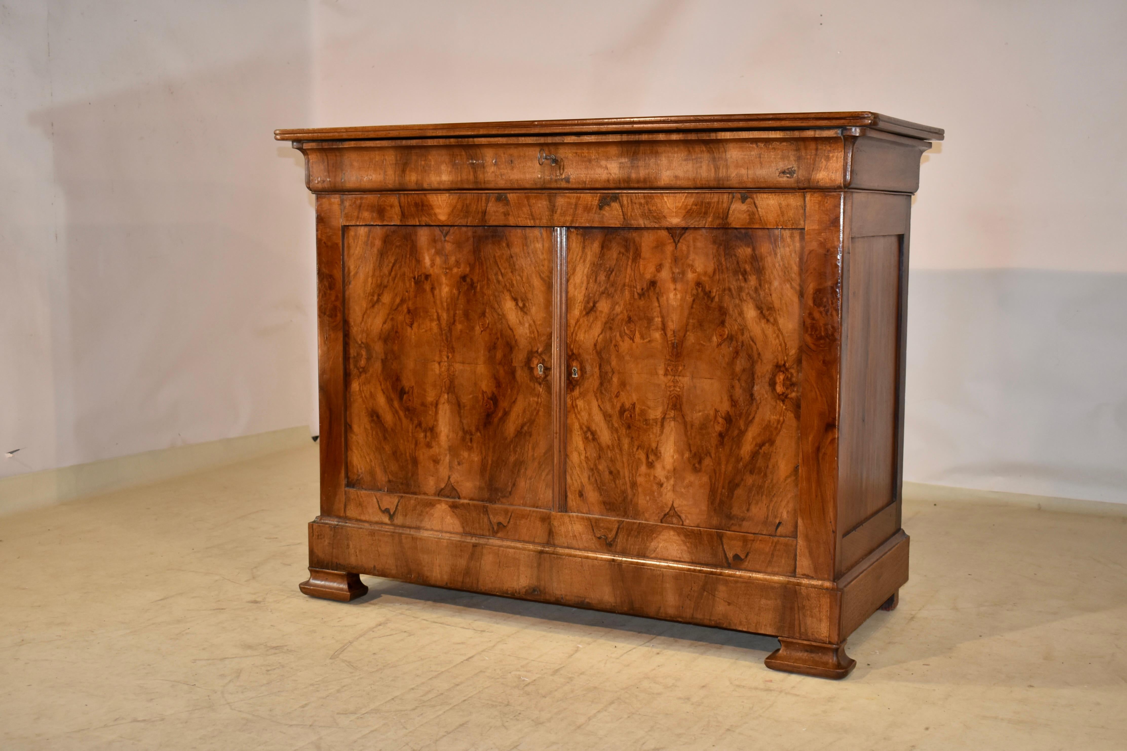 19th century Louis Philippe buffet from France with banding around the top, over simple paneled sides. There is a single drawer in the front over two doors, which open to reveal shelving. The doors are made from solid walnut and are veneered in book