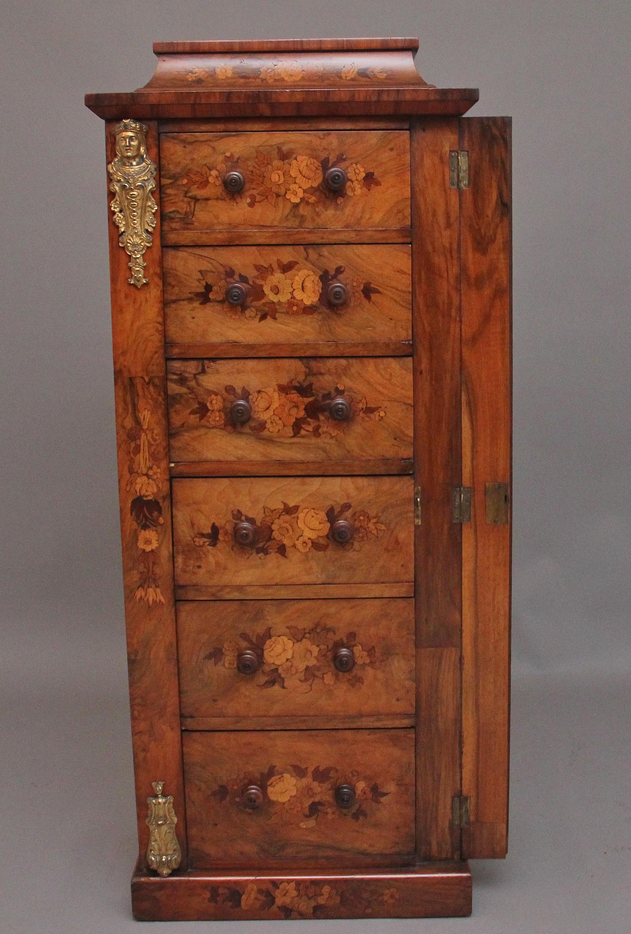 Un favoloso cassettone Wellington in noce e intarsio del XIX secolo, con cornice sagomata e modanata decorata con intarsi floreali sopra una combinazione di sei cassetti graduati rivestiti in mogano con maniglie originali a pomello in legno tornito.