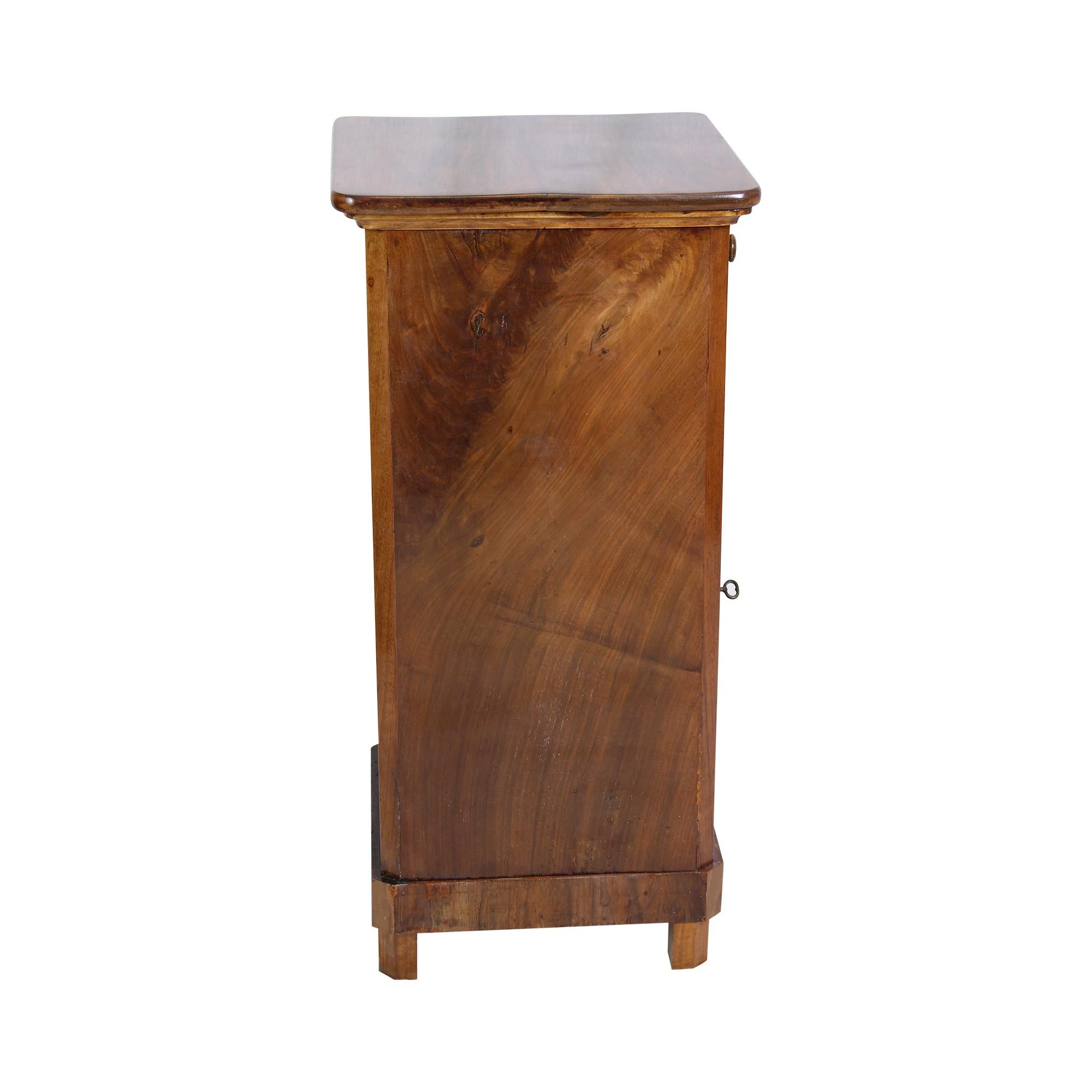 Beautiful Biedermeier bedside table in walnut veneer on softwood from Germany. There is a drawer at the top and a door at the bottom. The piece of furniture can be placed on its own as the back is also veneered. The furniture is in a very good,