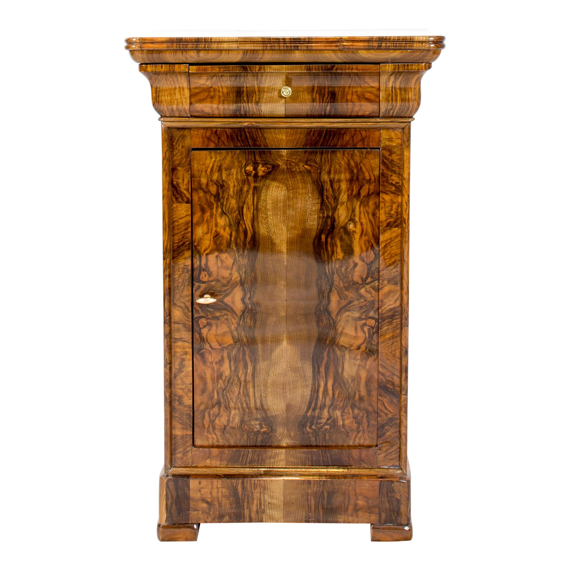 Beautiful Biedermeier walnut veneer nightstand or pillar cabinet from Germany. Back and shelf is made of spruce wood as usual. The opening handles are made of brass. There is a drawer at the top and a door below. The furniture is in a very good,