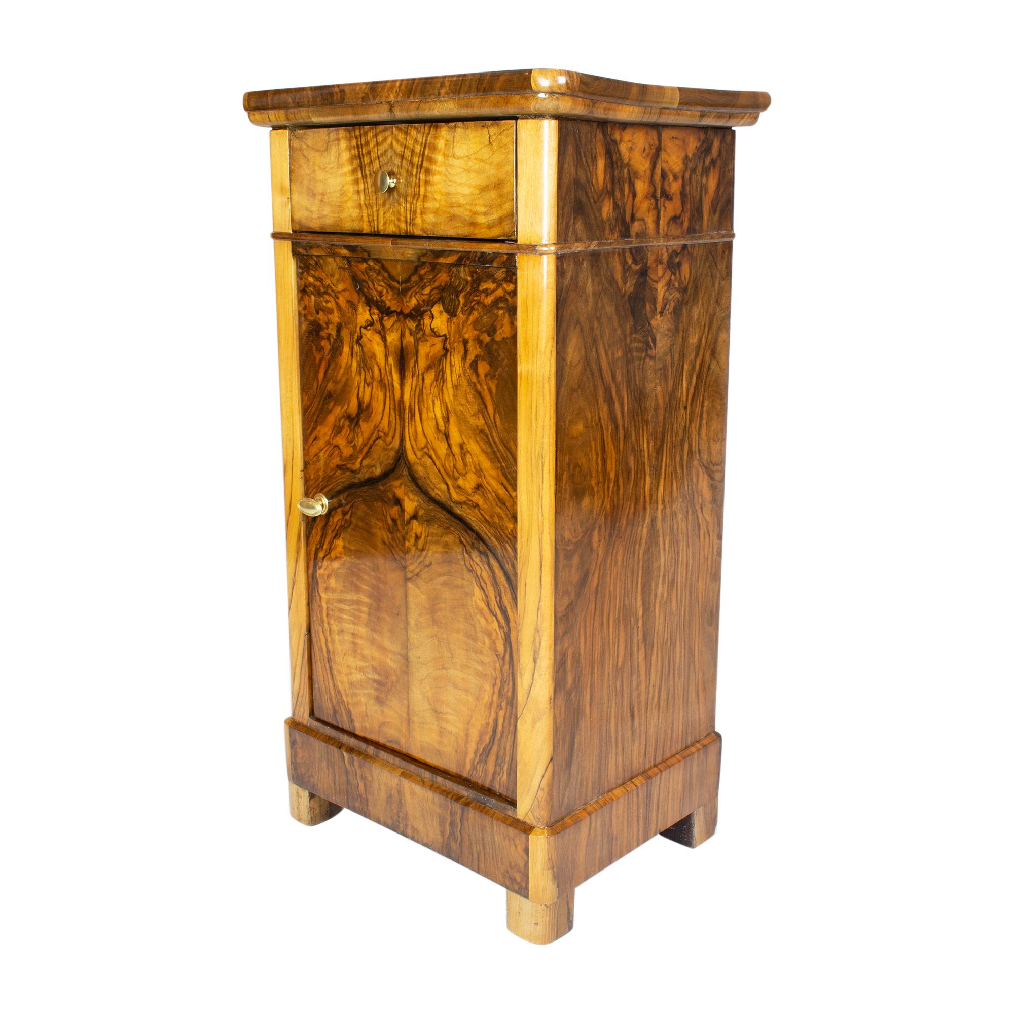 Beautiful Biedermeier walnut veneer nightstand or pillar cabinet from Germany. Back and shelf is made of spruce wood as usual. The opening handles are made of brass. There is a drawer at the top and a door below. The furniture is in a very good,