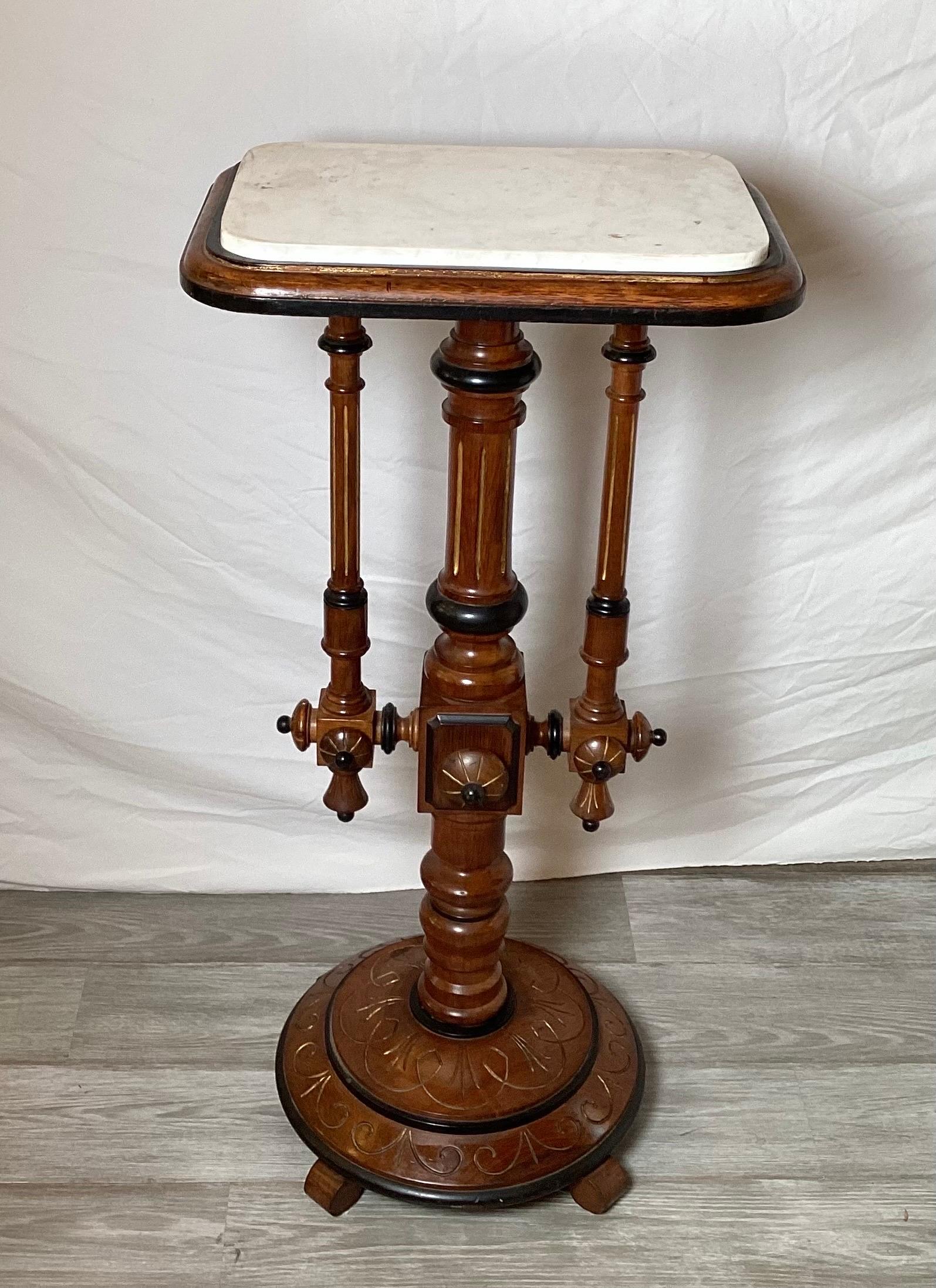 A Victorian walnut pedestal with ebonized and incised carvings with marble top, by Kilian Brothers, NYC