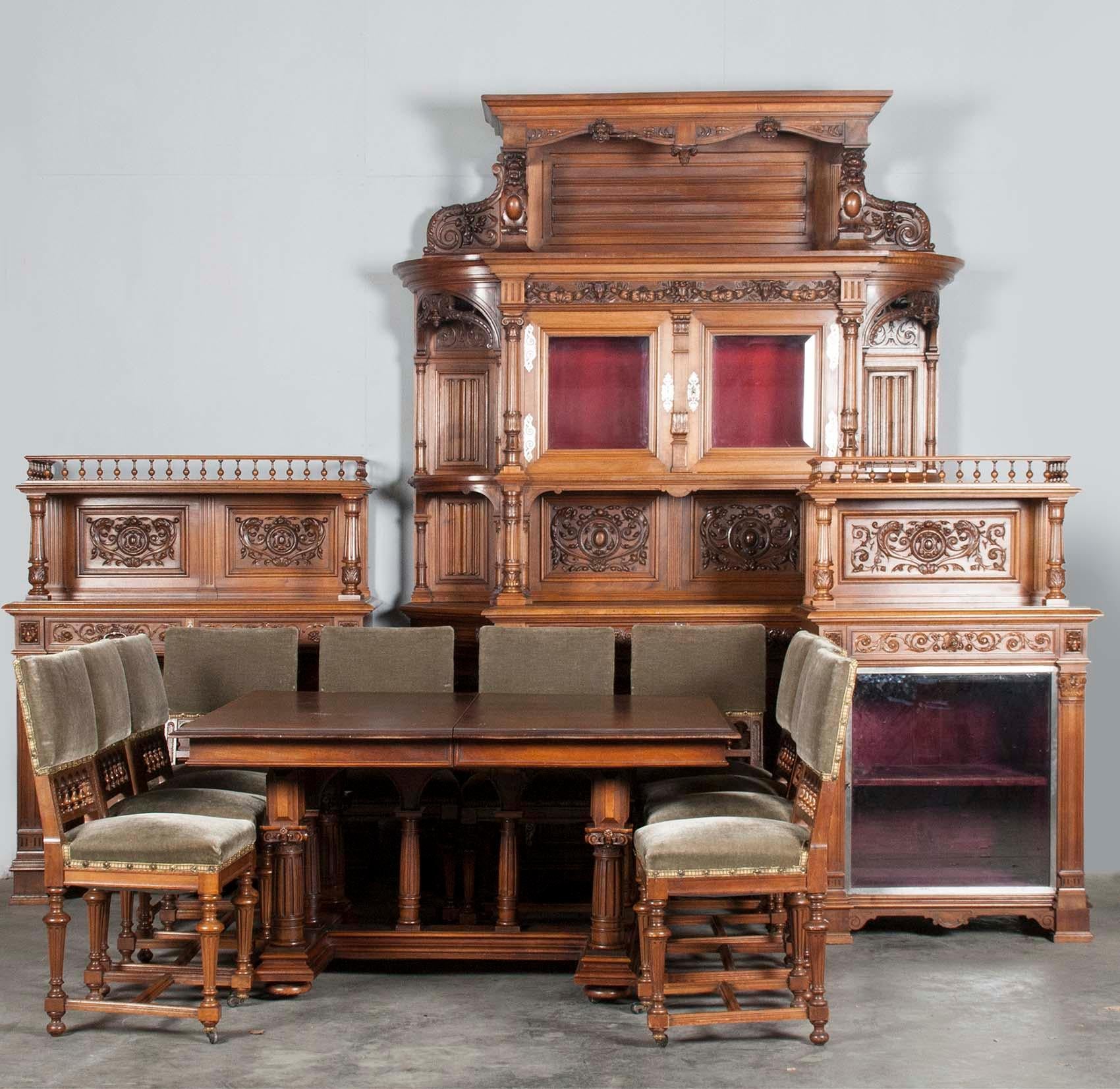 A French walnut Renaissance style dining suite. The dining room consists of: Buffet cupboard, server cabinet, silver cabinet, table and 10 chairs. Hand carved from solid walnut in Renaissance style. Richly ornamented with Gothic panels, lion heads