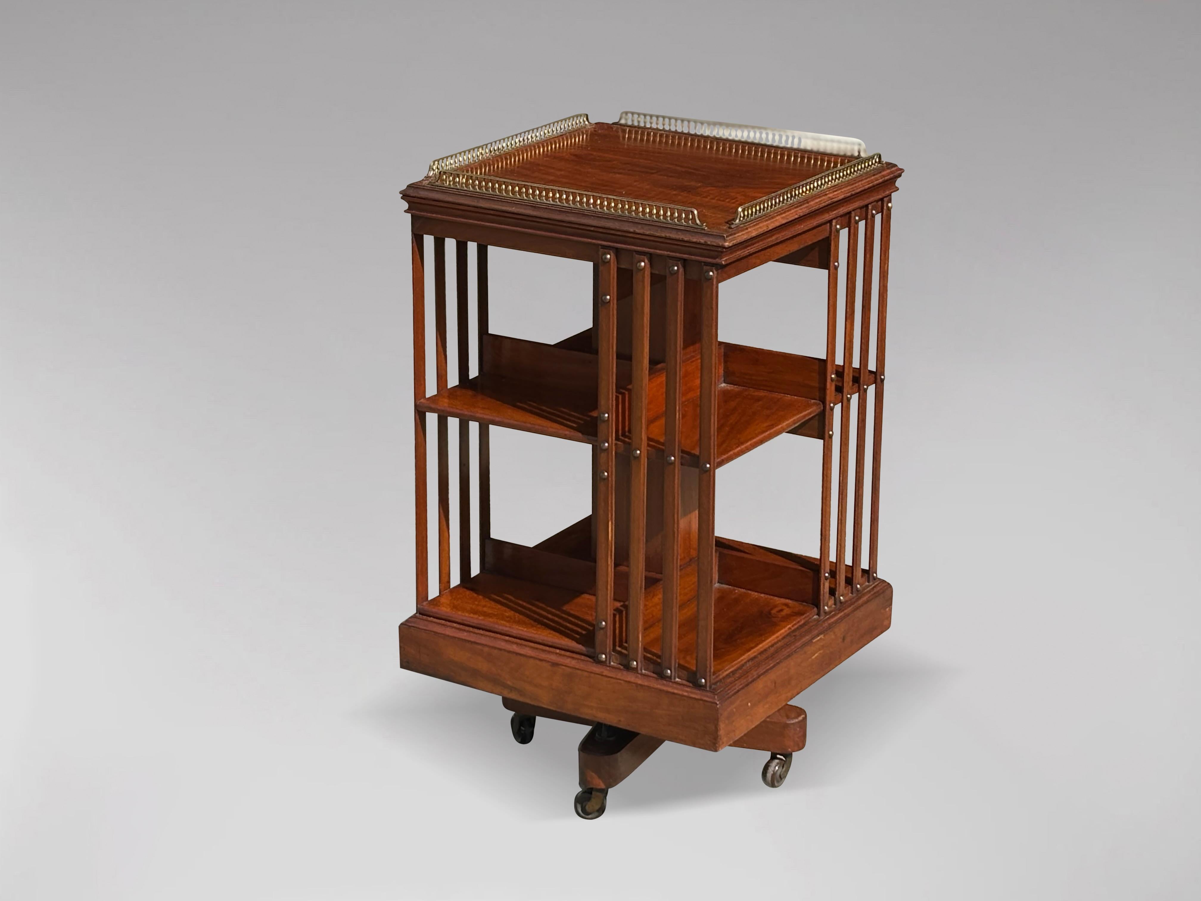 An attractive 19th century mahogany revolving bookcase by Maple & Co. London Paris with slatted sides, brass gallery top, moulded edge, above two-tiered bookshelf with quarter sections divided by inlaid slats running from top to the base fastened