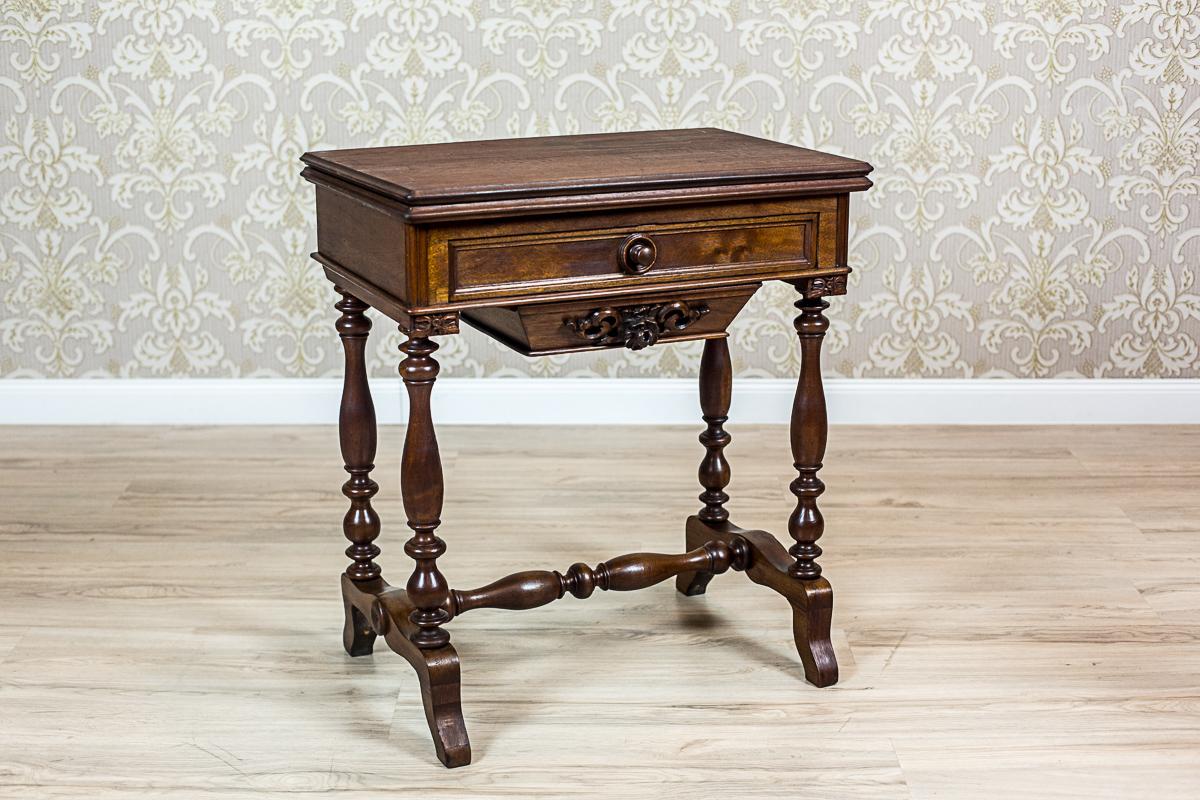 We present you this sewing table that can be used in two ways: as a desk and as a card table. That can be done by lifting the top up, and rotating it on the spindle installed underneath.
This article of furniture is made of walnut wood and walnut