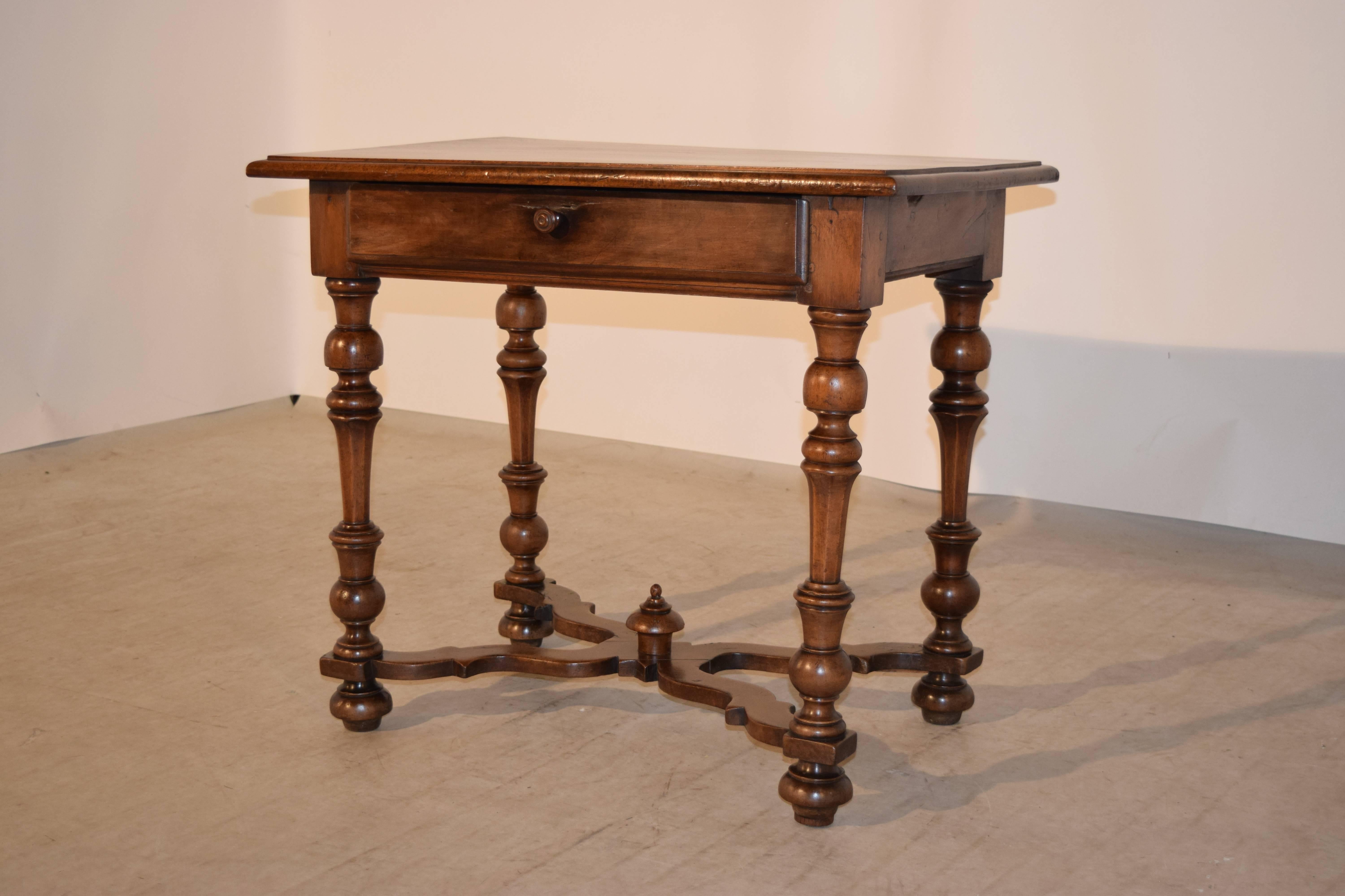 19th century walnut side table from France. The top is beveled around the edge and follows down to a simple apron containing a single drawer, supported on hand turned legs which are joined by serpentine shaped cross stretchers, decorated with a