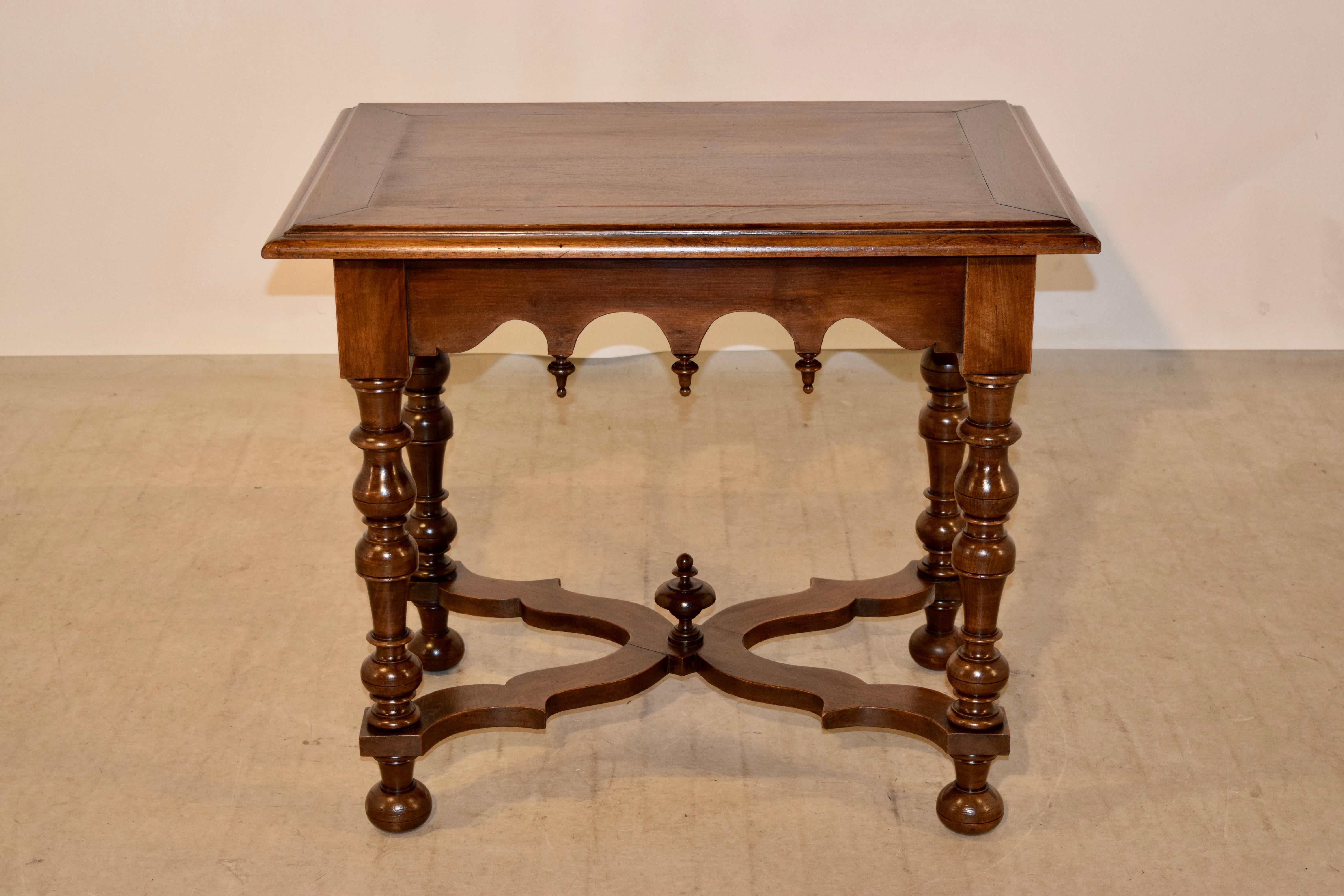 19th century walnut side table from France with a banded top which has a molded and beveled edge as well, following down to a scalloped apron with hand-turned finial decorations. The legs are hand-turned and are joined by a hand scalloped stretcher,