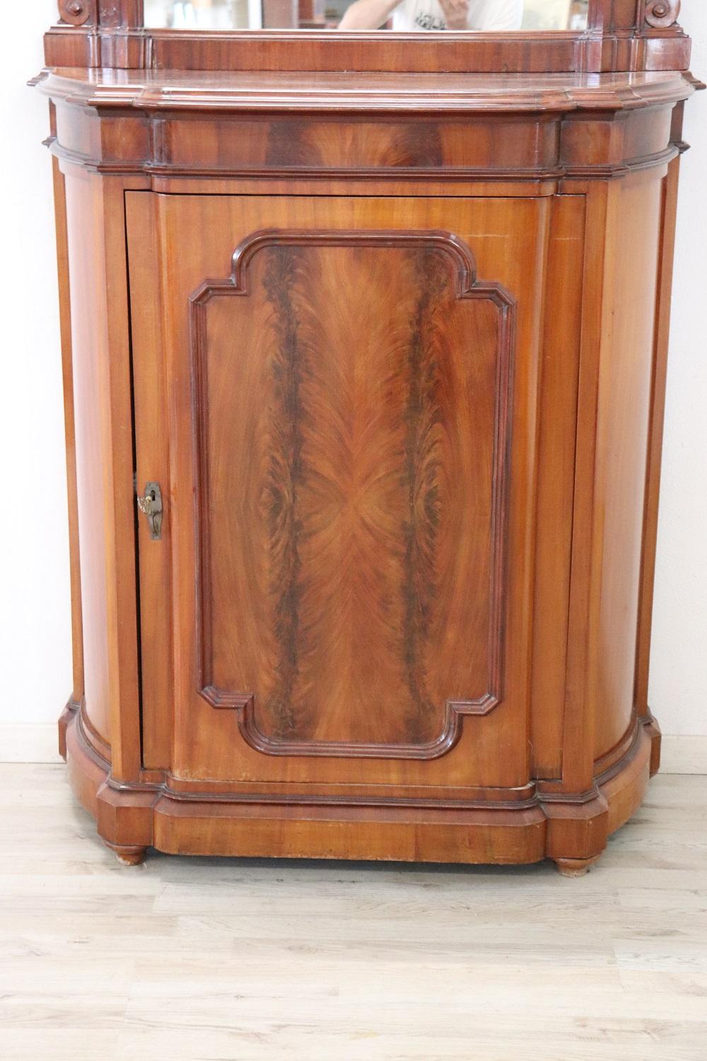 Small cabinet very simple and linear characterized by walnut wood with root in the central part of the door. Equipped with two internal shelves. In the upper part a beautiful large mirror with a medallion carved in the tip. Perfect conditions.