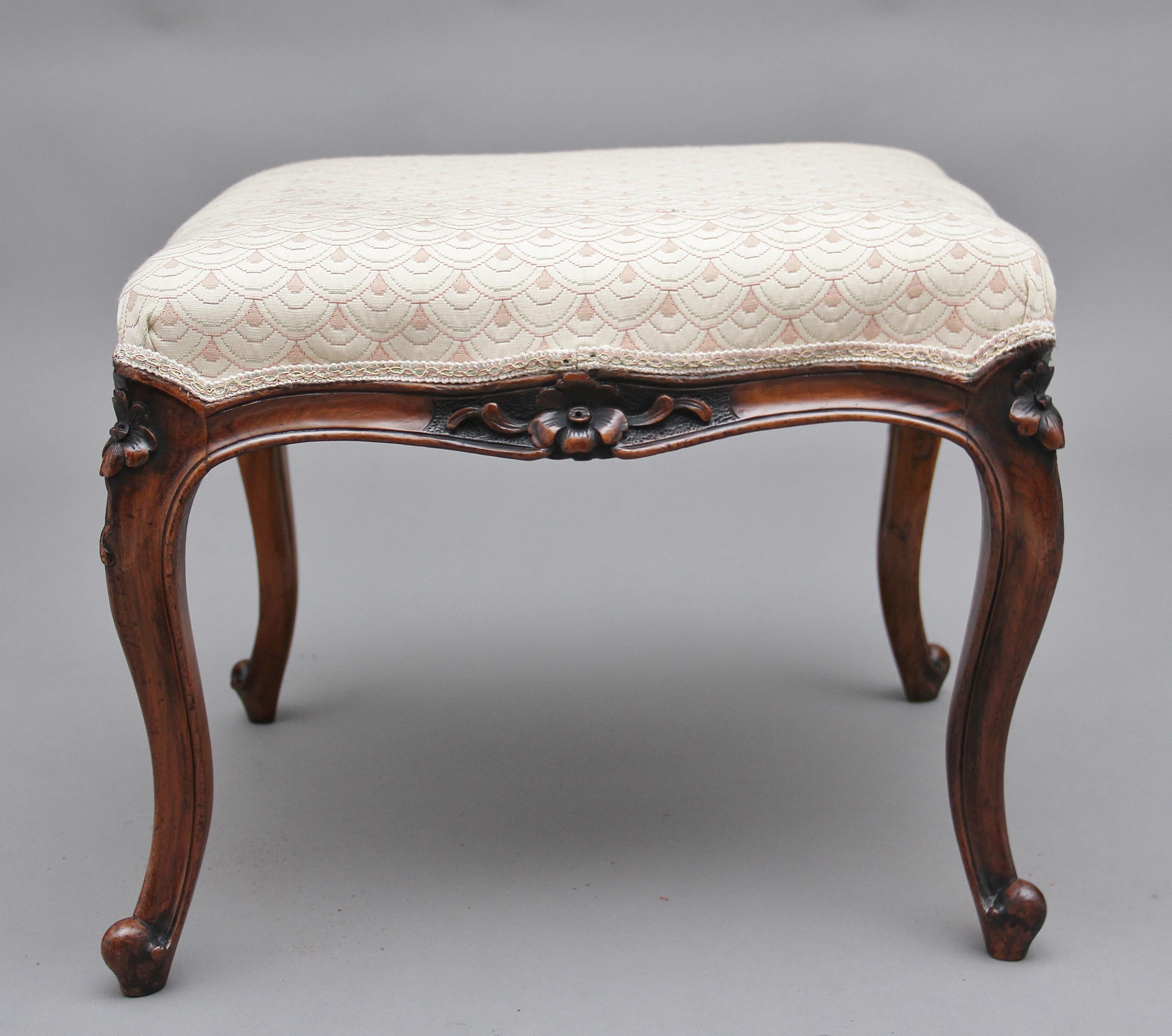 19th century walnut stool having a cream colored stuff over upholstered seat with a decorative pattern, the foliate carved arched edge on cabriole legs, circa 1860.
  