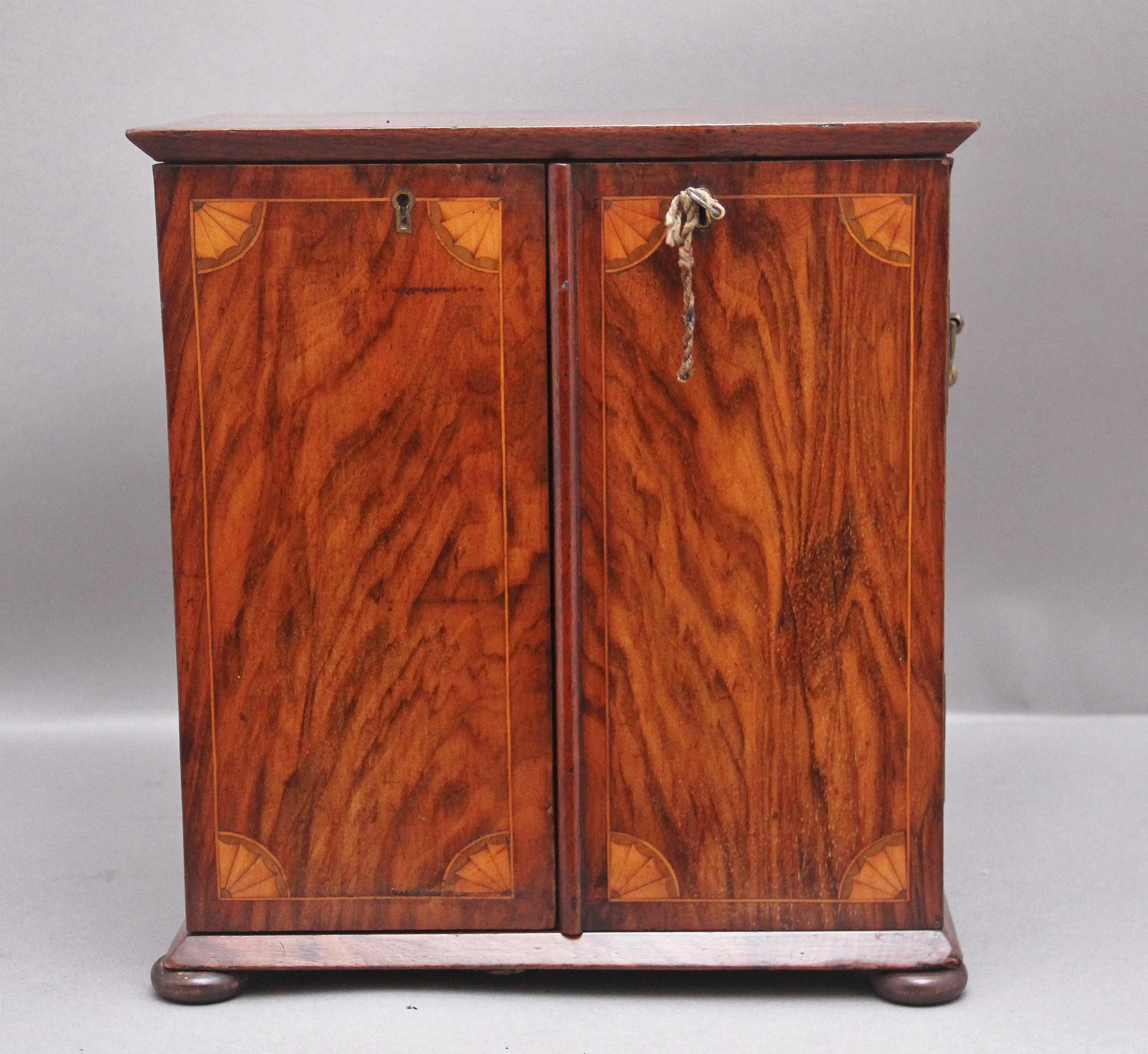 19th Century walnut table cabinet, having a lovely figured top with an inlaid oval panel with shell decoration above two hinged cupboard doors opening to reveal a combination of two short over two long mahogany lined drawers with the original