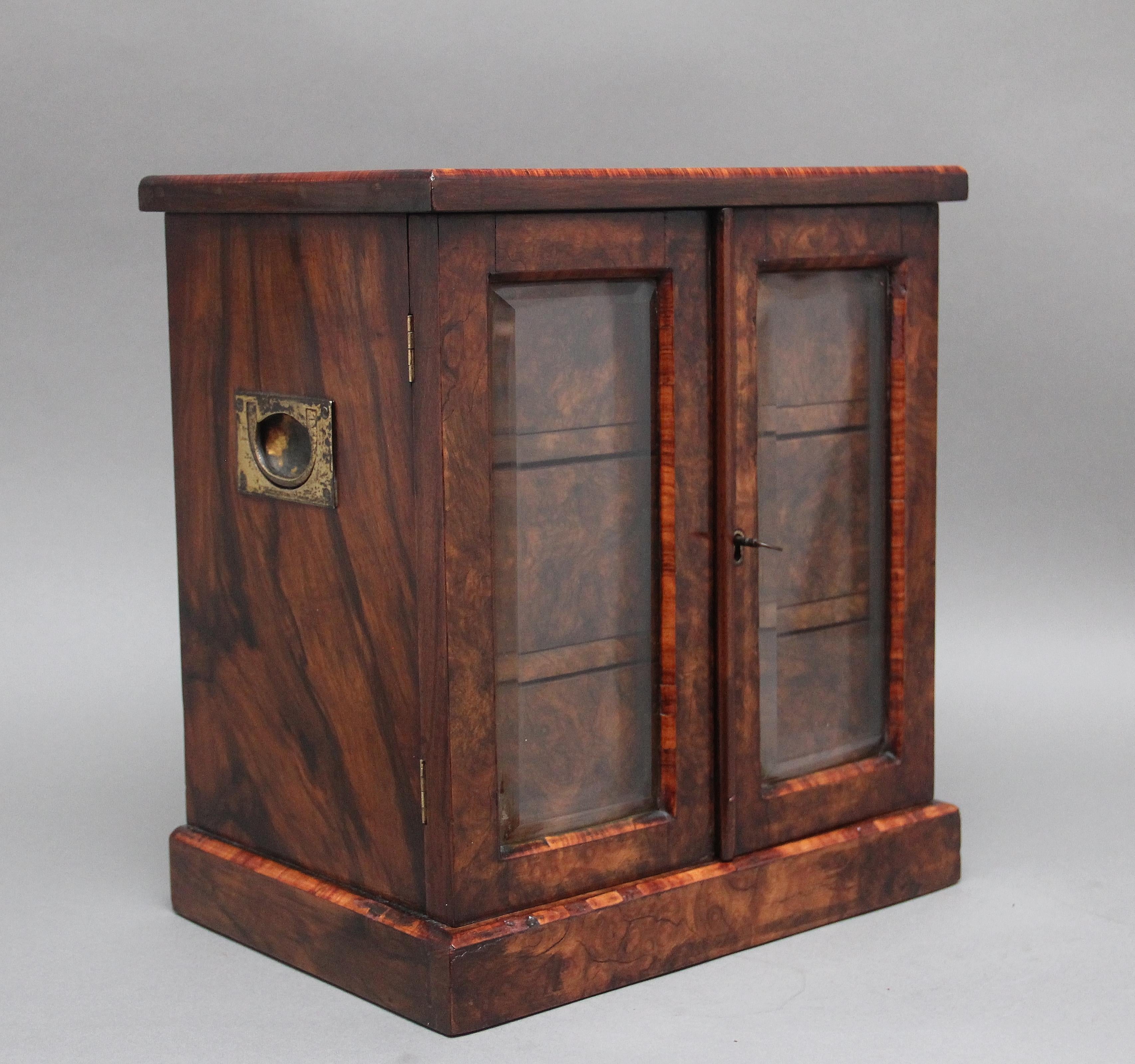 A fine quality 19th Century burr walnut table cabinet, having a nice figured top with decorative inlay along the edge and a brass plaque at the centre, two hinged glazed doors below opening to reveal three mahogany lined drawers with the original