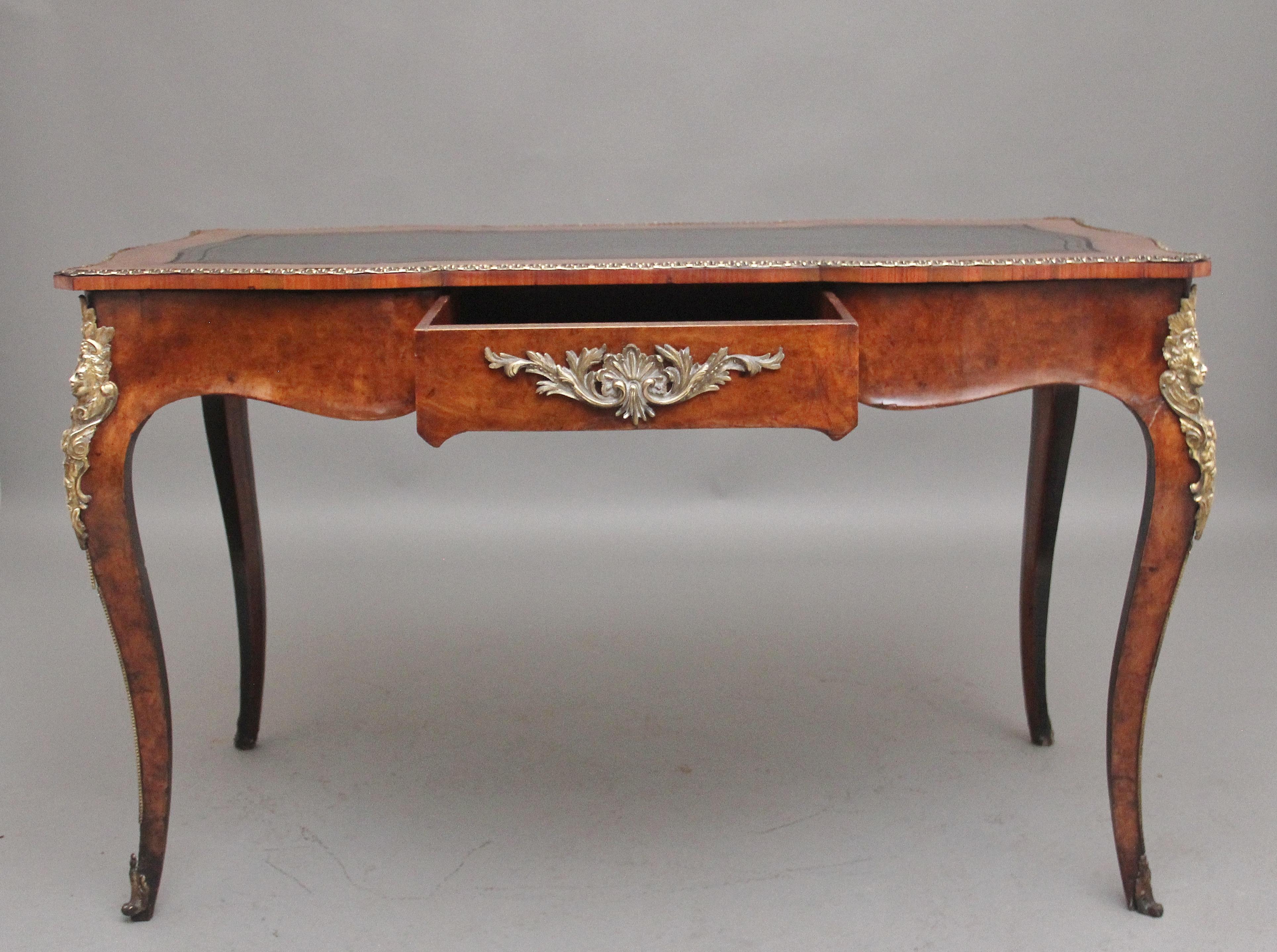 A lovely quality 19th Century walnut writing table, the shaped top having a black leather writing surface decorated with blind and gold tooling, finely carved ormolu moulded edge running along the edge of the top above a shaped apron running along
