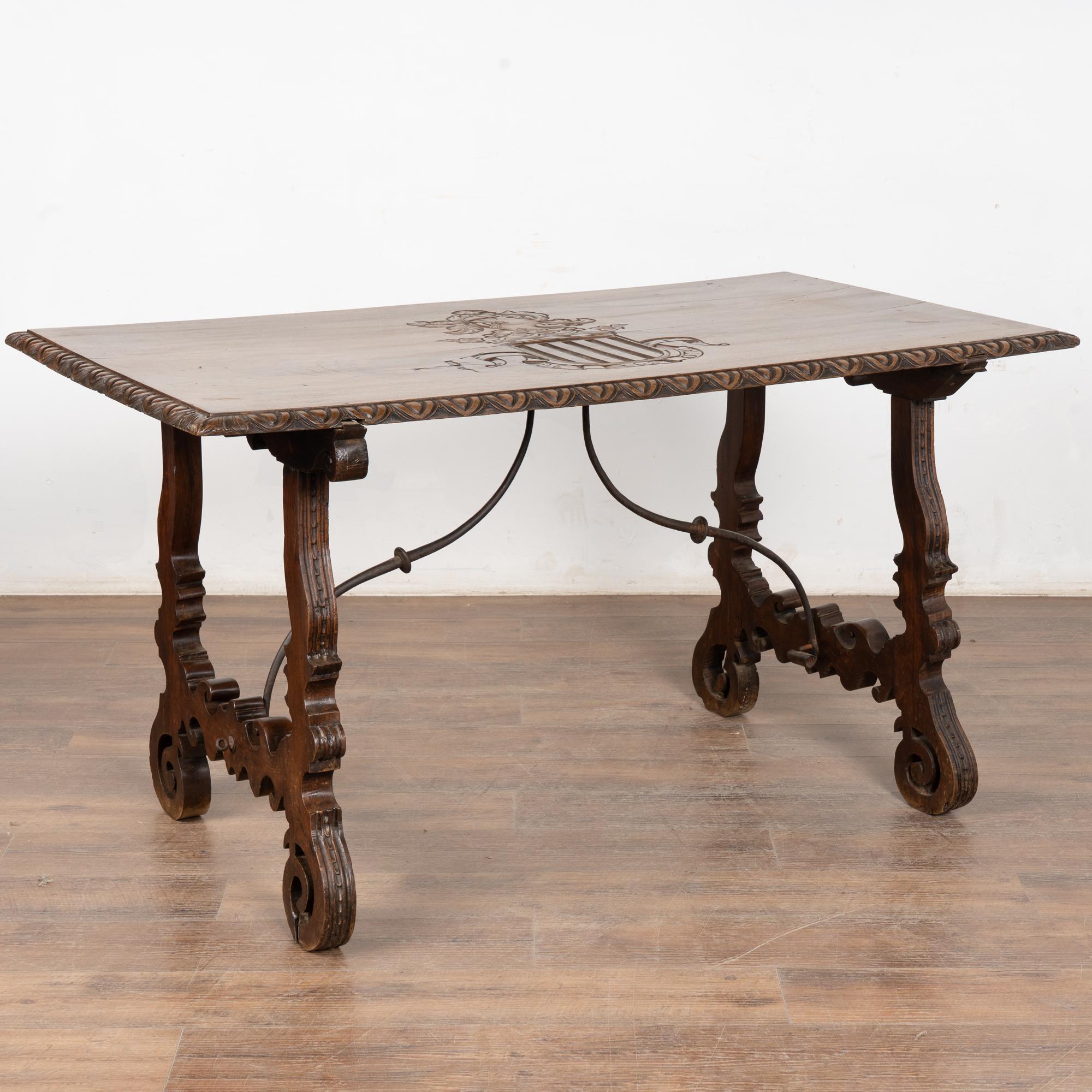 Table à écrire en noyer d'Espagne avec des pieds tournés décoratifs en forme de harpe et un châssis en fer à volutes.
Notez le beau blason familial sculpté au centre et les mots 