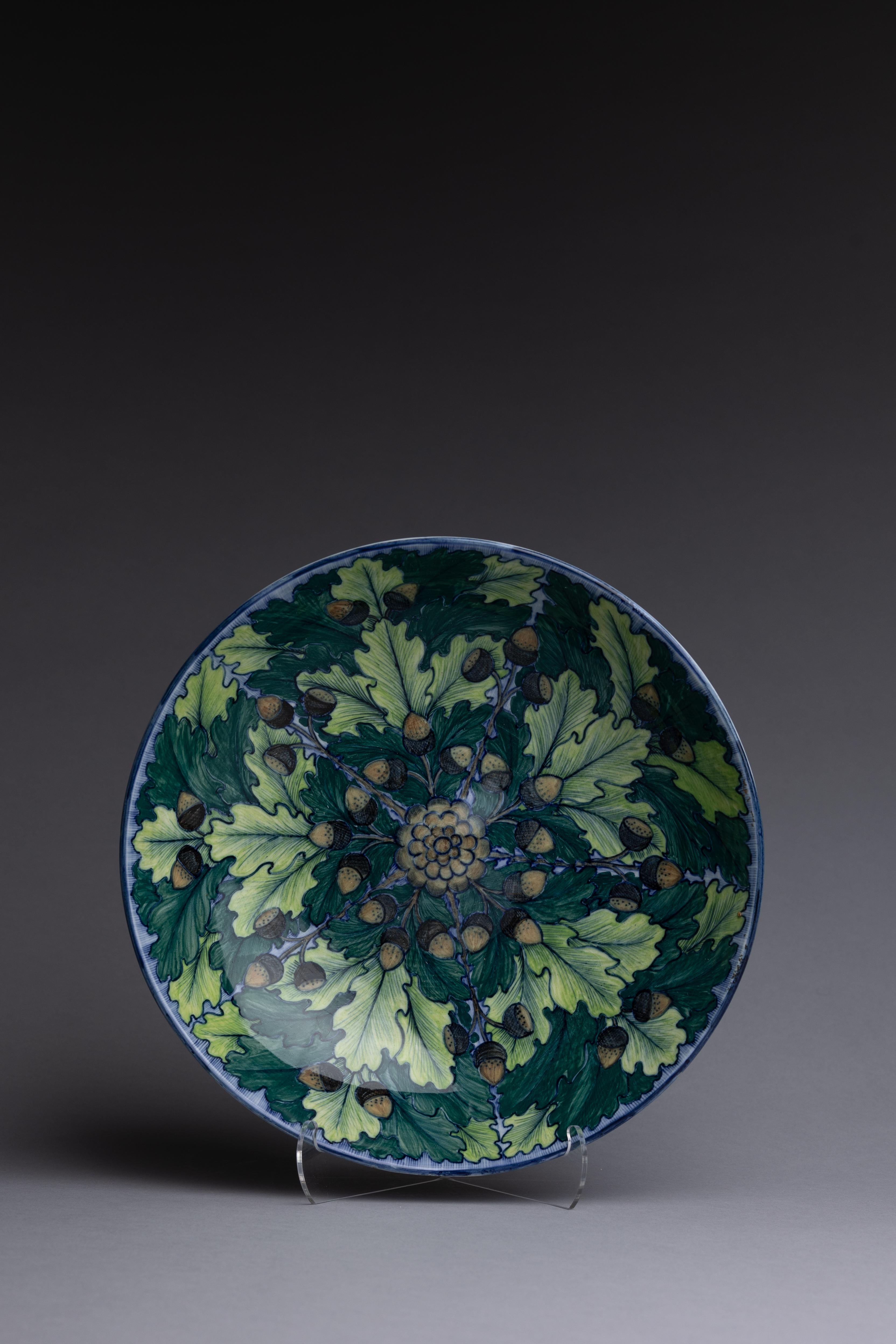A shallow Wedgwood center bowl beautifully hand-painted with a mesmerizing design of oak leaves and acorns swirling around a pinecone at the center. The artist is unidentified but has signed the reverse 