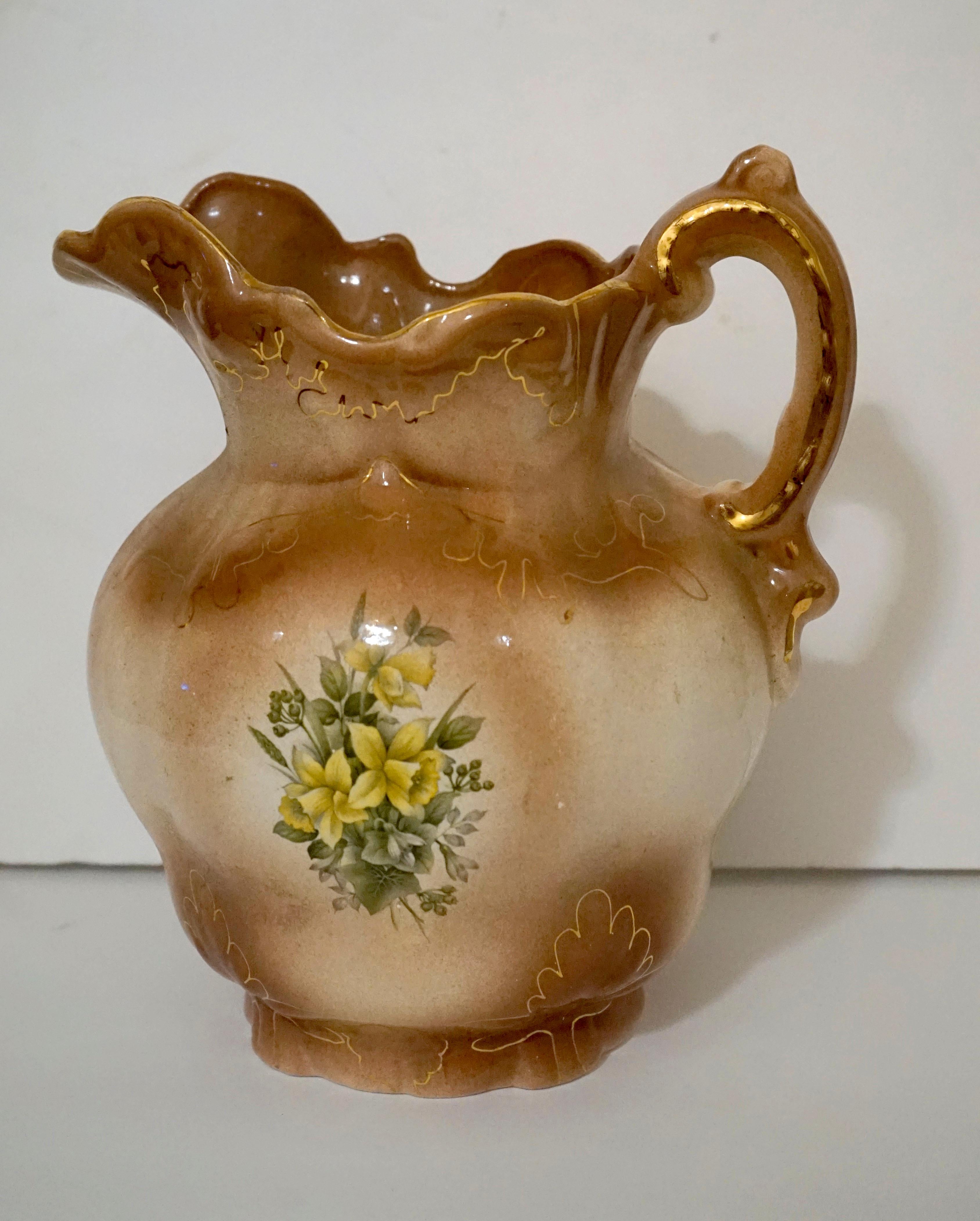 Queens Ware is the mark on this pitcher and basin set made in England in the mid to late 1800s by Wedgwood. It is also known as creamware, a technique English potters used to achieve the tan color. The set is hand painted in soft beige and accented