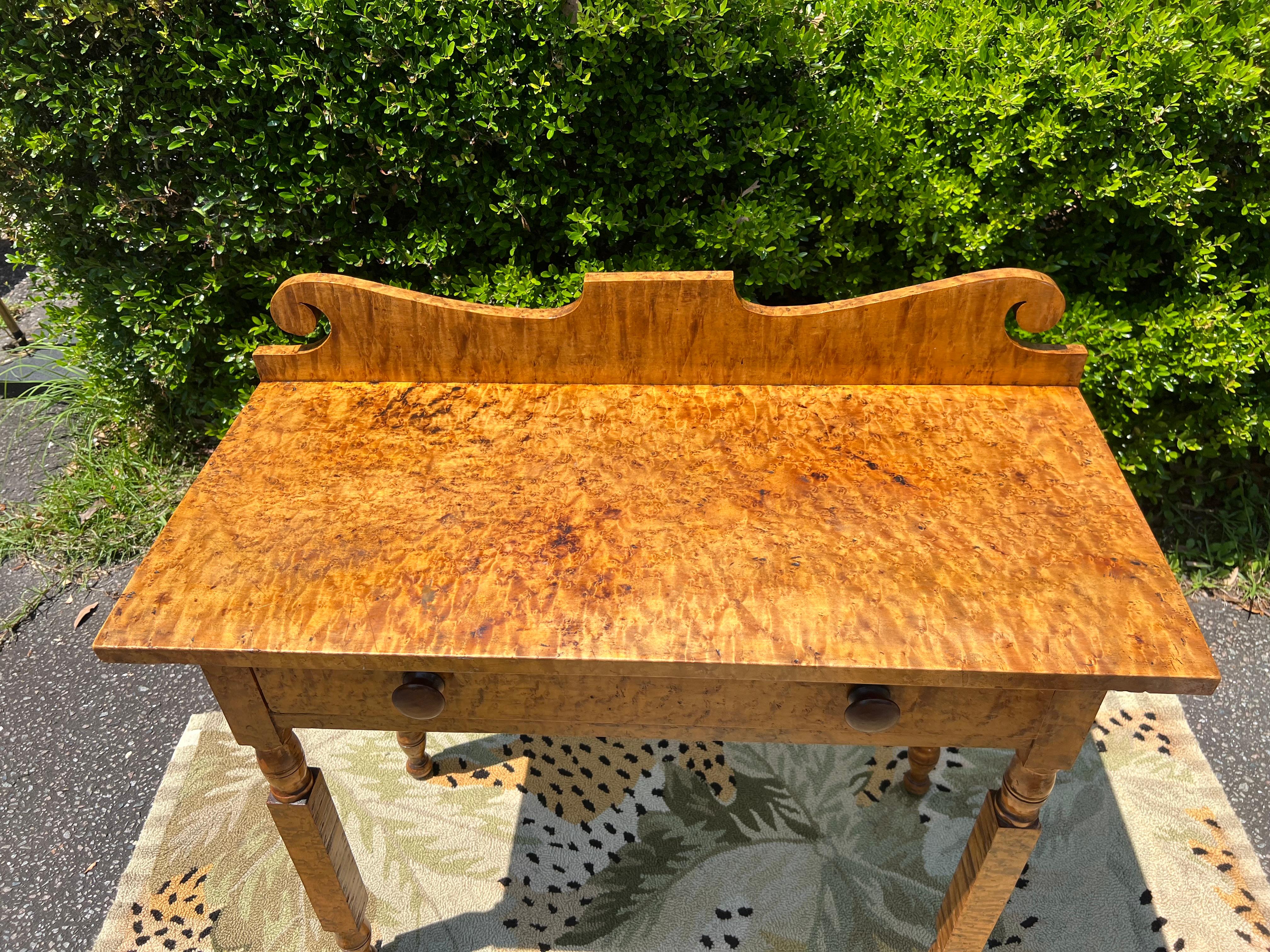 A nice size with a shaped open back splash and a single apron drawer with fine wood knob pulls. Raised on finely turned legs. The drawer is hand planed and the dovetail predates machines. 19TH C ANTIQUE TIGER MAPLE & BIRDS EYE MAPLE EMPIRE SABER LEG