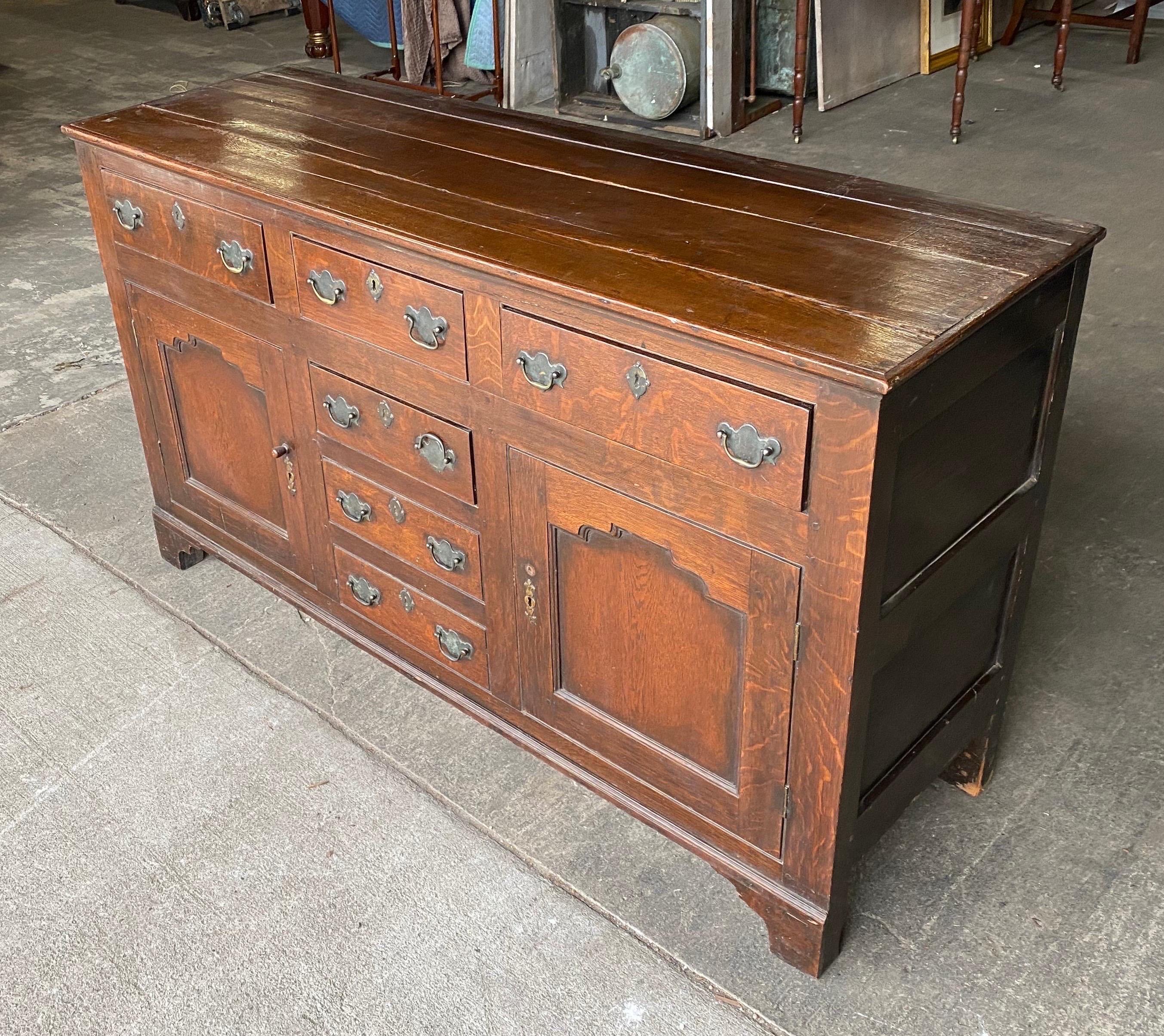 19th century Welsh oak dresser base. 3 drawers over 2 doors and 2 faux bottom drawers, paneled doors and bracket feet.
