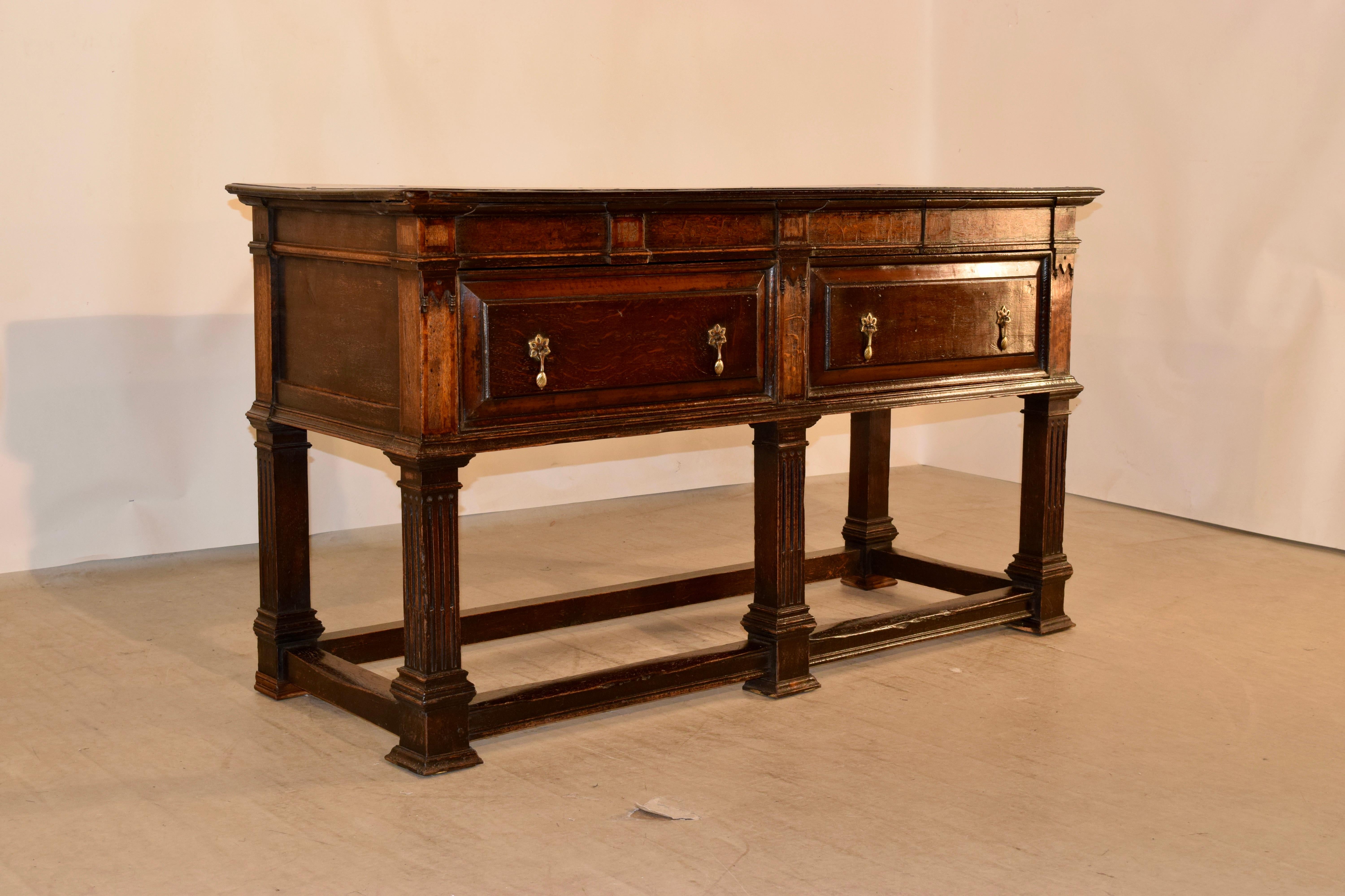 19th century oak sideboard from Wales. The top is made from two planks and has beveled edges and pegged construction. This follows down to paneled sides and two drawers in the front, beneath an inlaid apron and molded edge. The piece is supported on