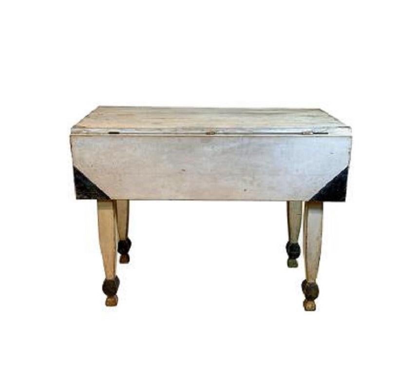 Whimsical 19th century white painted drop-leaf table with black detail. The rectangular top with a black painted corners on each drop-leaf and raised on four white legs of square section which taper to the top and bottom terminating in a black