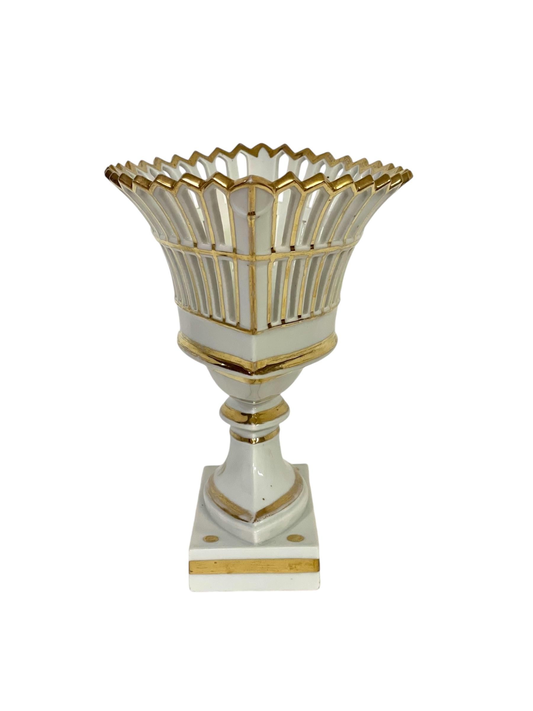 Un elegante cesto di frutta traforato in porcellana parigina e parcel gilt, realizzato in due pezzi uniti dal bullone originale in ottone. Il cesto ha una forma ovale e poggia su una solida base rettangolare, evidenziata da generose bande dorate.