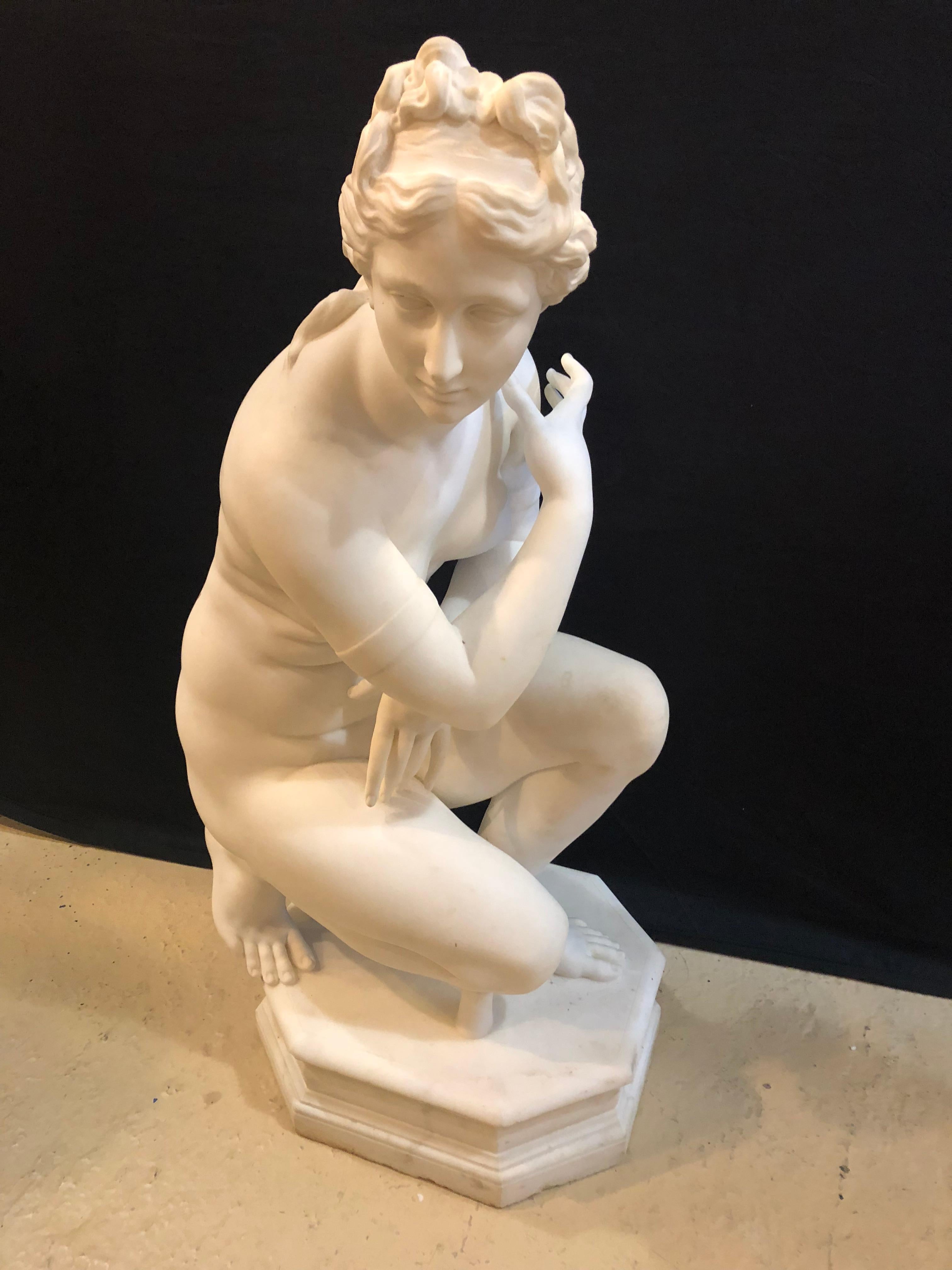 A 19th century white Carrara marble of a nude life sized figure kneeling. She is everything one could dream of. This fantastic life-sized semi-nude maiden is trying desperately to hide her ample breasts while kneeling upon a rock. The detail is