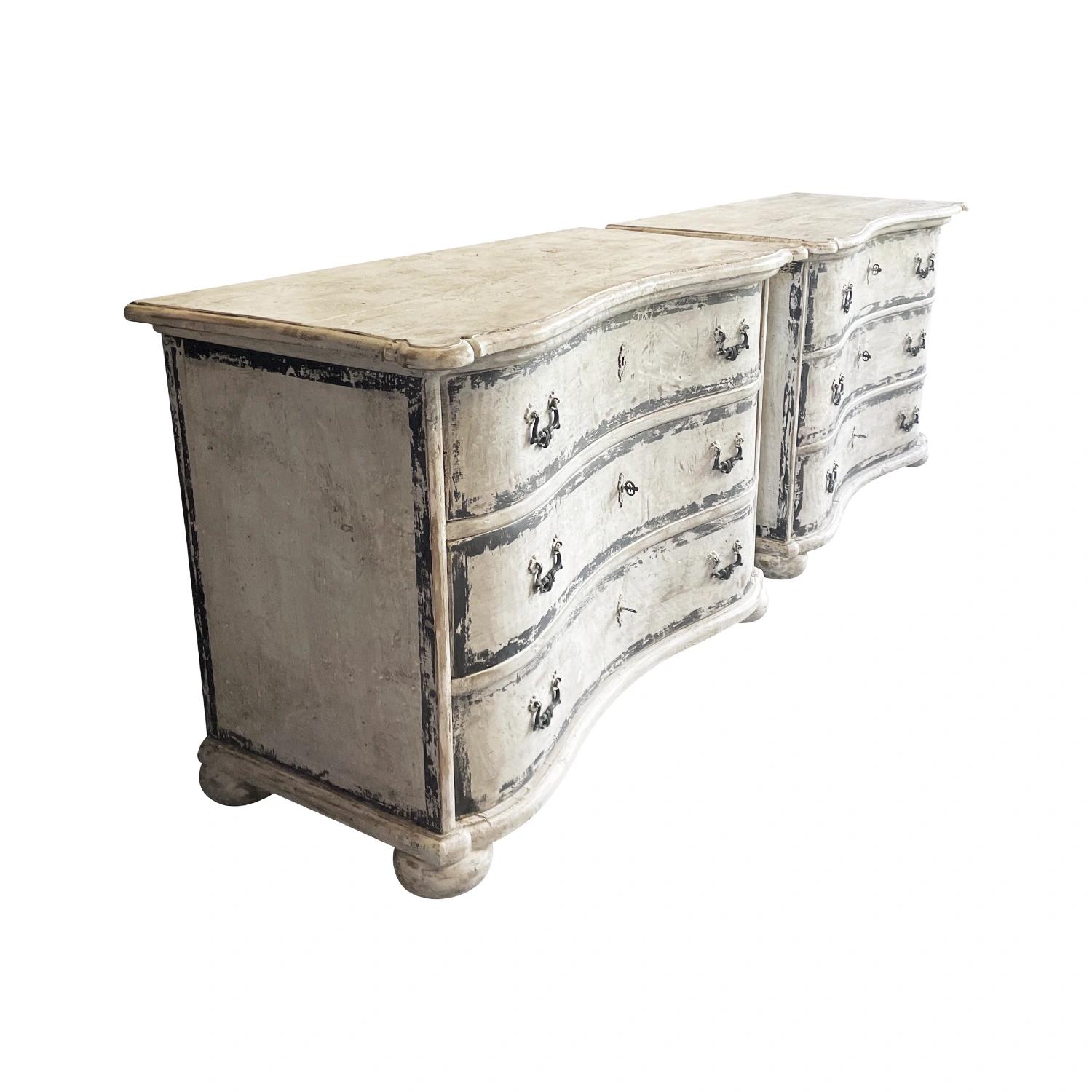 An antique French pair of Provencal chests of drawers or commodes made of hand crafted Pinewood with bowed fronts and an ecru color aged patina, in good condition. The painted commodes have a slightly raised rectangular tops with round corners. The