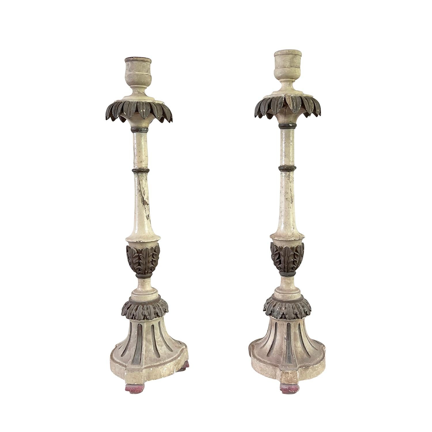 An antique set of two Gustavian candle holders with palm décor foliage ornaments, in good condition. The hand carved Pinewood candle stick is patinated in ecru and grey and is accentuated by hand crafted metal cups in a silvery patina. Elevated by