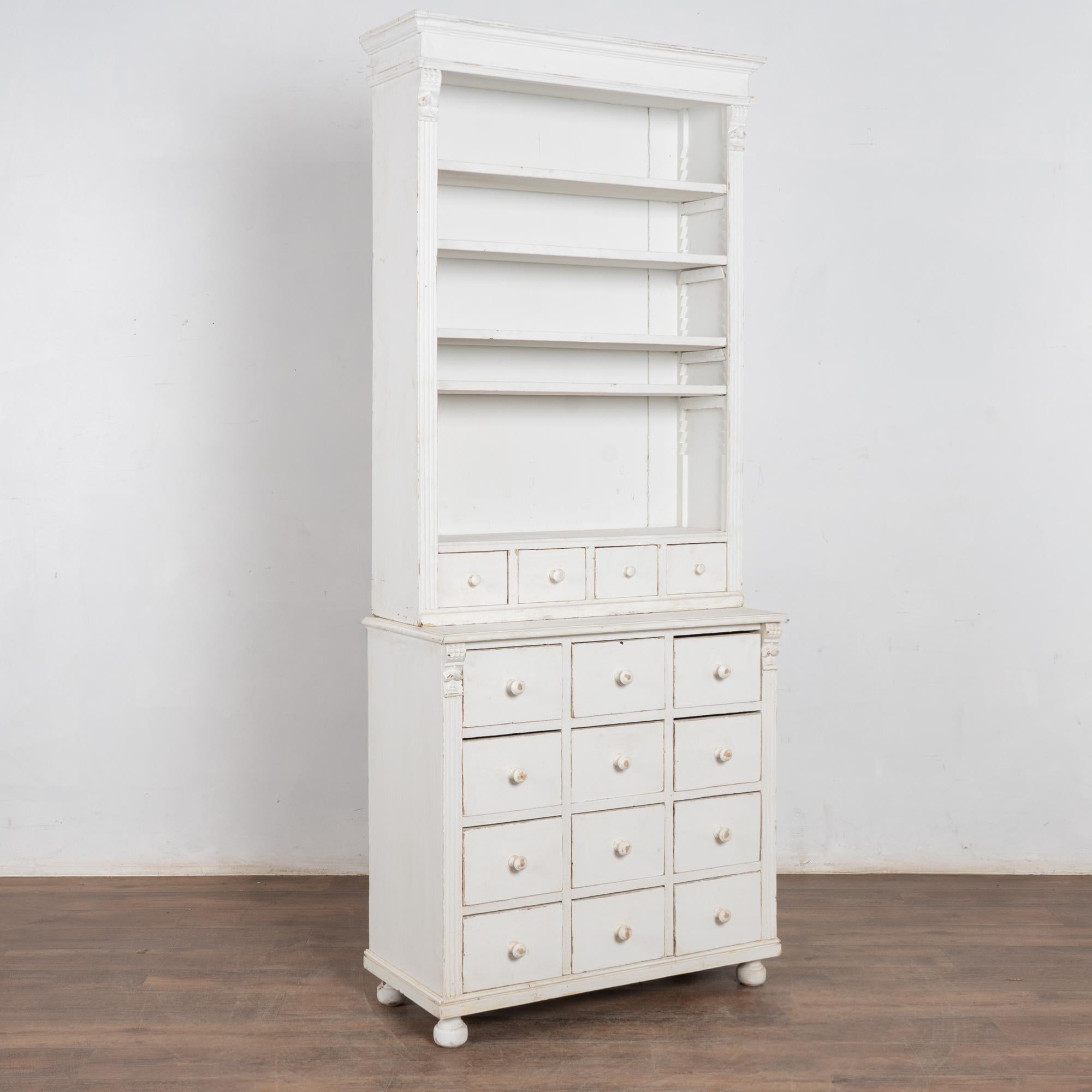 This country pine display cabinet may also be used as a bookcase, with adjustable shelves and 16 apothecary style drawers to add versatile storage and display options. 
Restored, strong and stable, ready to use. Later painted white and lightly