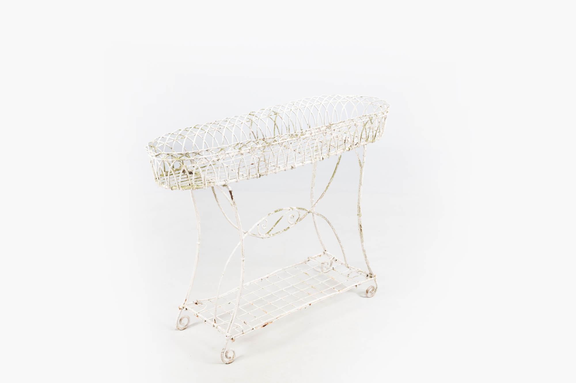 19th Century white painted metal wirework plant stand featuring galleried basket top and scrolled feet. Pieces such as this were favoured in Victorian garden rooms and conservatories to display flowering pot plants. Traditionally produced in