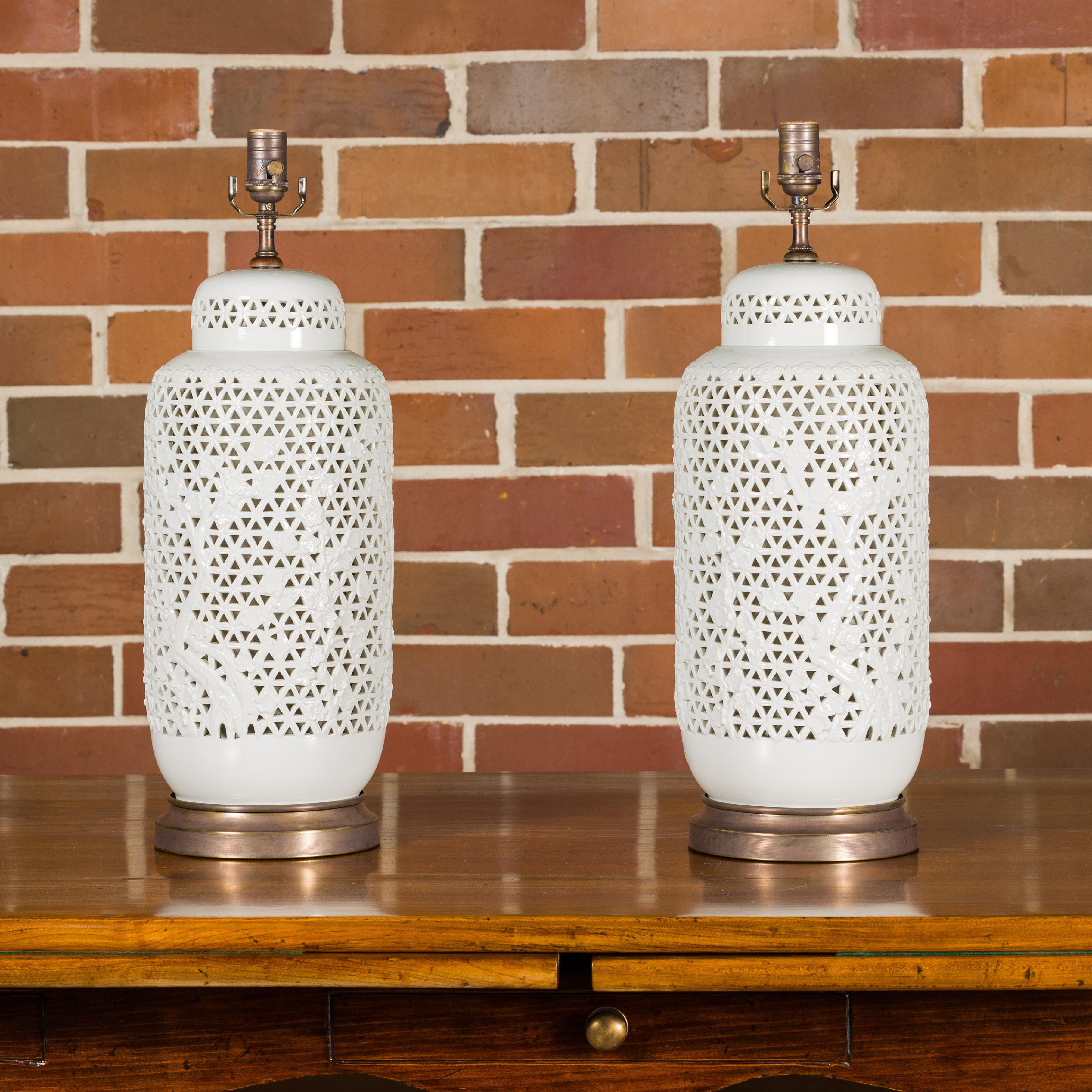 Paire de vases en porcelaine blanche à décor floral et ajouré du XIXe siècle transformés en lampes de table câblées pour les États-Unis et montées sur des bases circulaires. Admirez le charme intemporel de cette paire exquise de vases en porcelaine