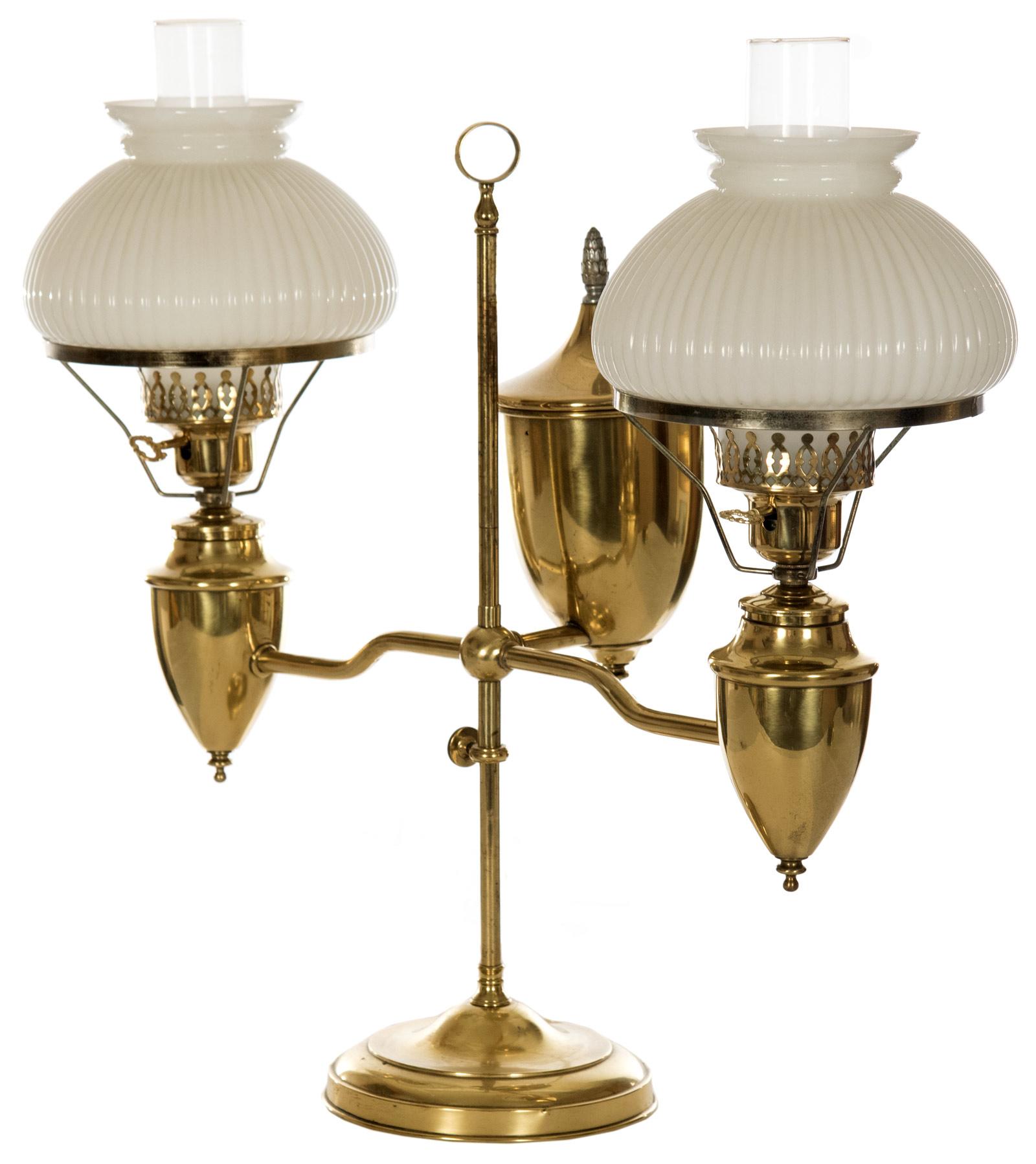 An electrified, late 19th century double student gas lamp with ribbed white case glass shades raised on brass fuel reservoirs, the arms affixed to an adjustable central stem, all raised on a stepped domed base. Measures: 22 ½ x 25 x 10 inches.