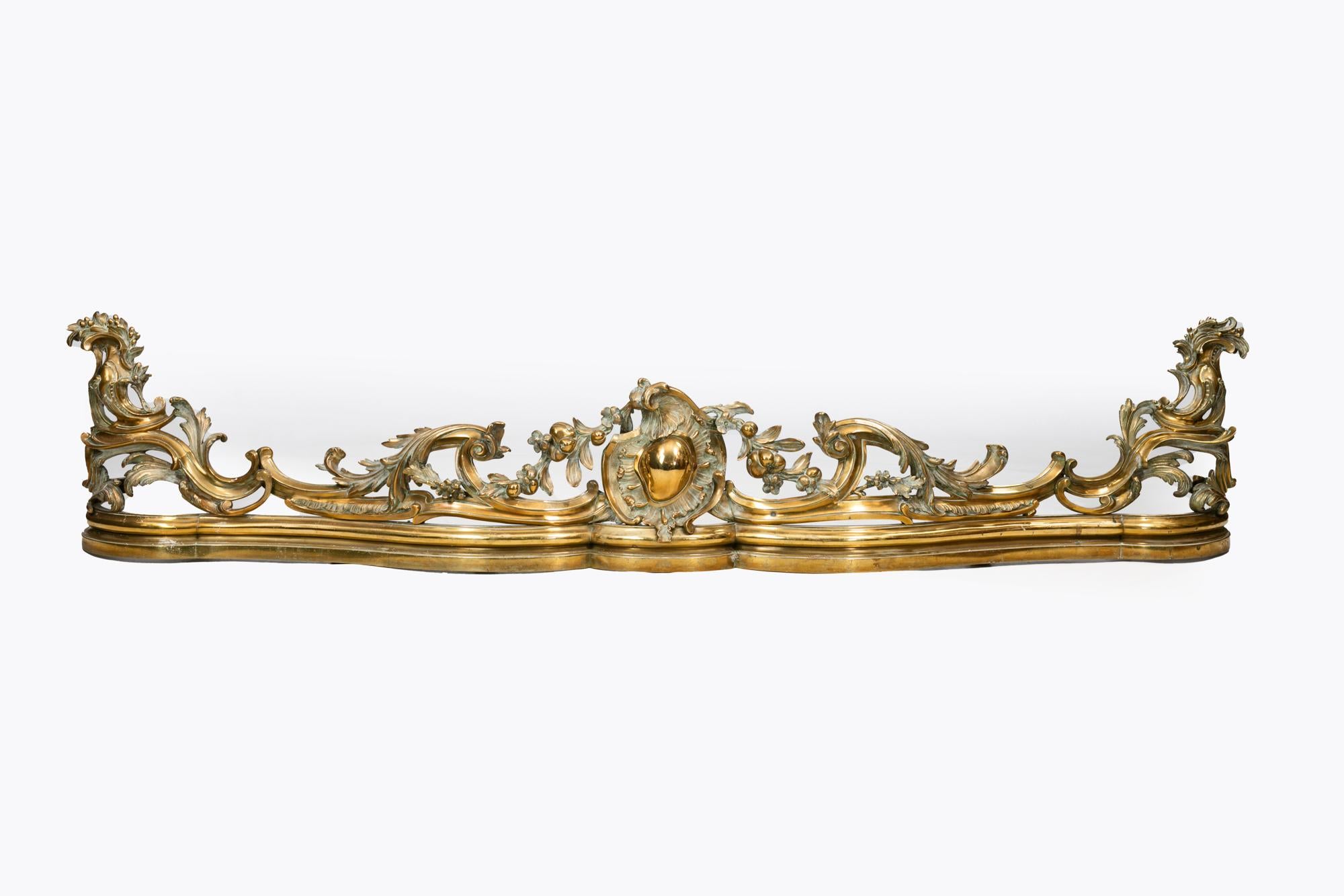 Parafuoco in ottone William IV del XIX secolo, di forma serpeggiante, con cartiglio centrale affiancato da fogliame stilizzato, volute e foglie d'acanto.