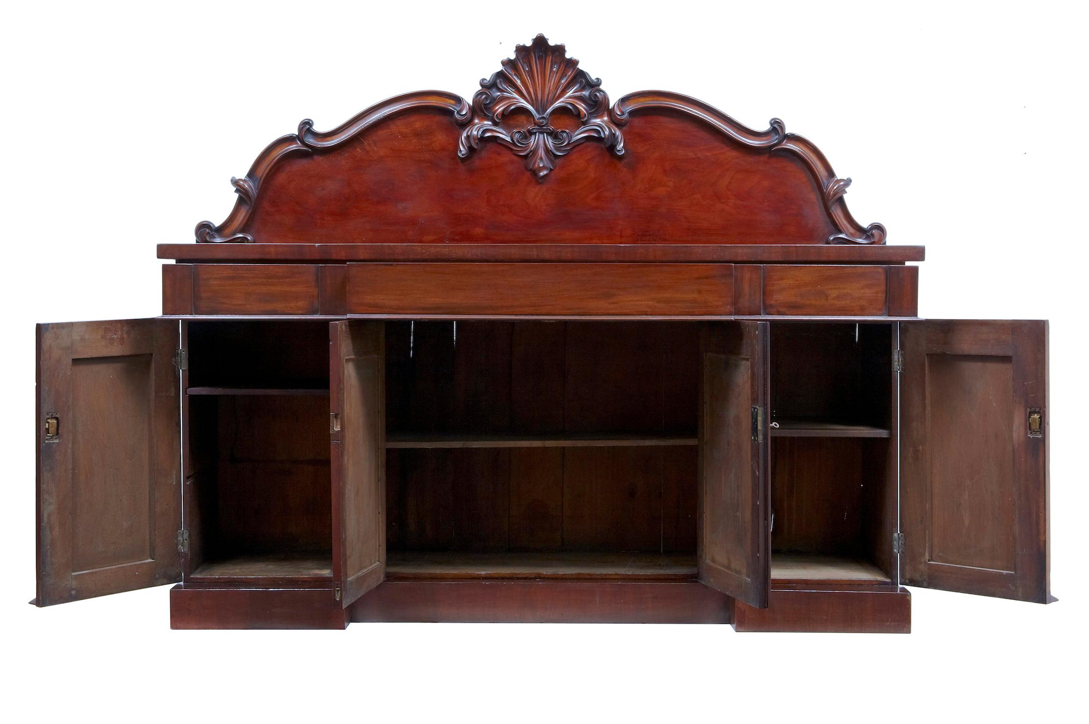 Good quality mahogany sideboard circa 1835. Lovely rich color. Main feature is the deeply carved stylized floral/shell central carving. 2 parts. 3 drawers above a double door cupboard containing a single drawer, flanked either side by a single door