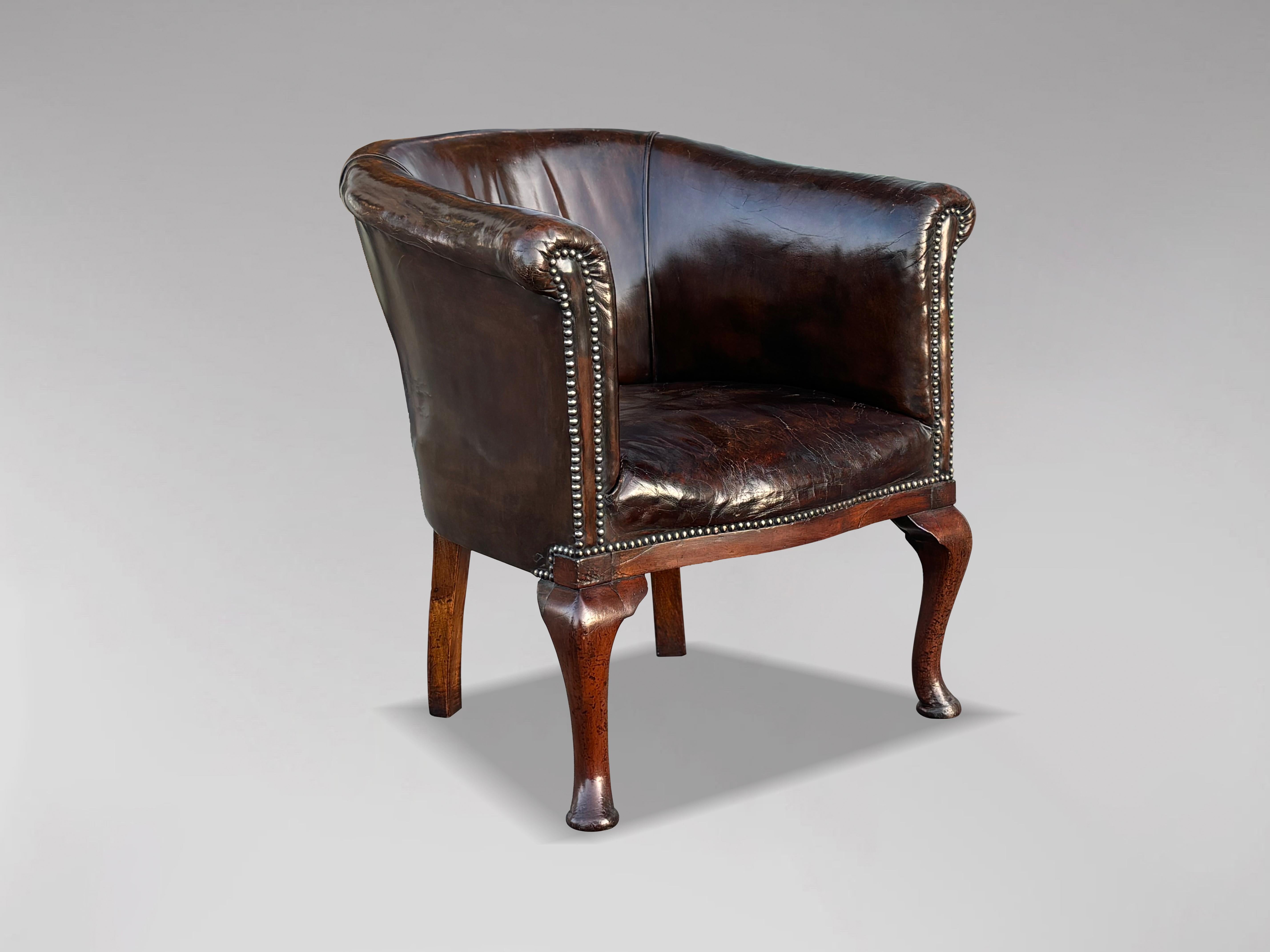 This 19th-century William IV period brown leather library desk tub armchair combines elegance, comfort, and timeless craftsmanship. The substantial, well-shaped frame features a gently curved back and scrolled arms, all meticulously covered in the