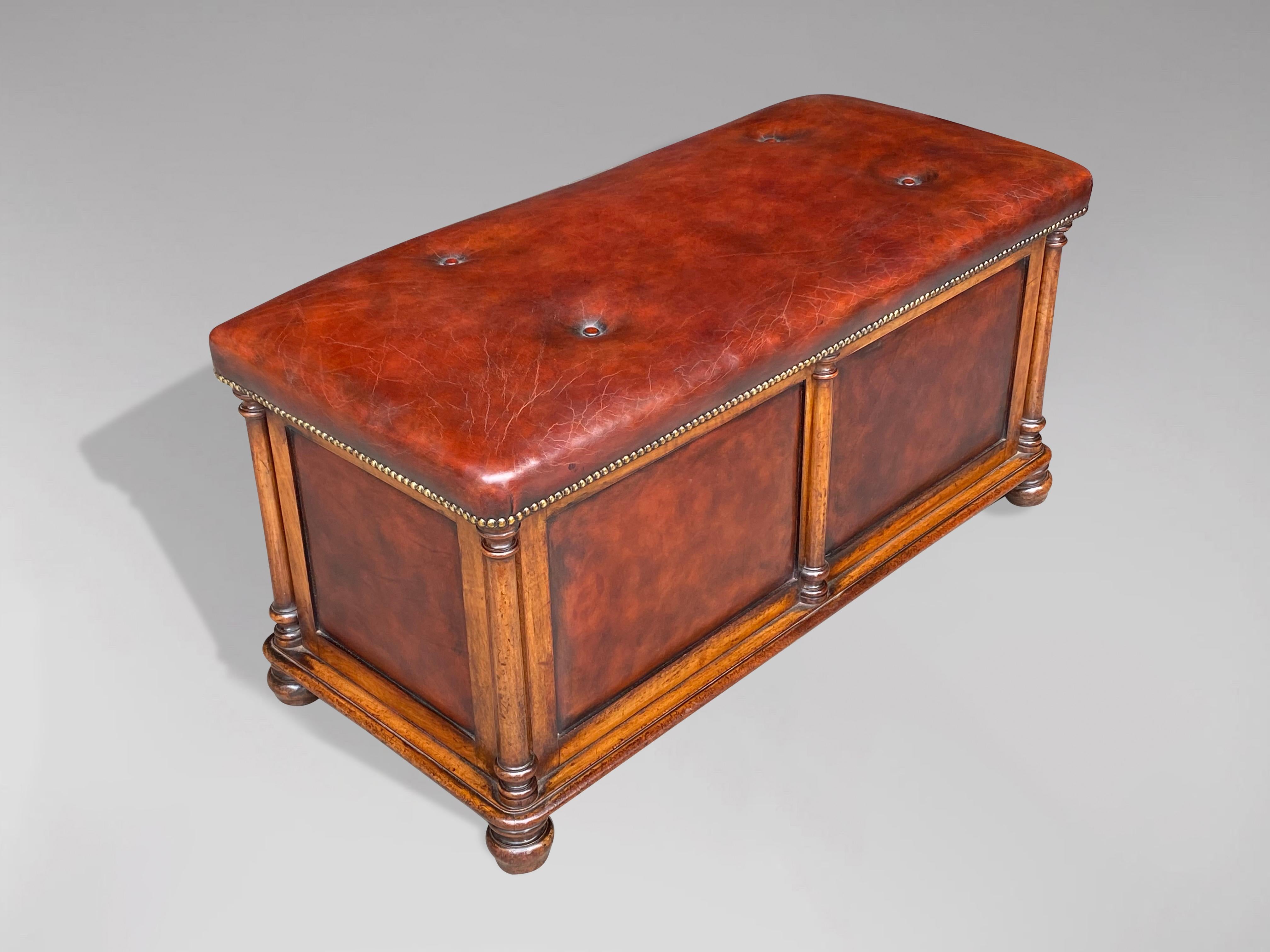 A fine quality early 19th century, William IV period walnut and leather ottoman. Deep red coloured buttoned leather seat above a well figured walnut and leather panelled base with turned walnut columns to each corner. Raised on four bun feet. The