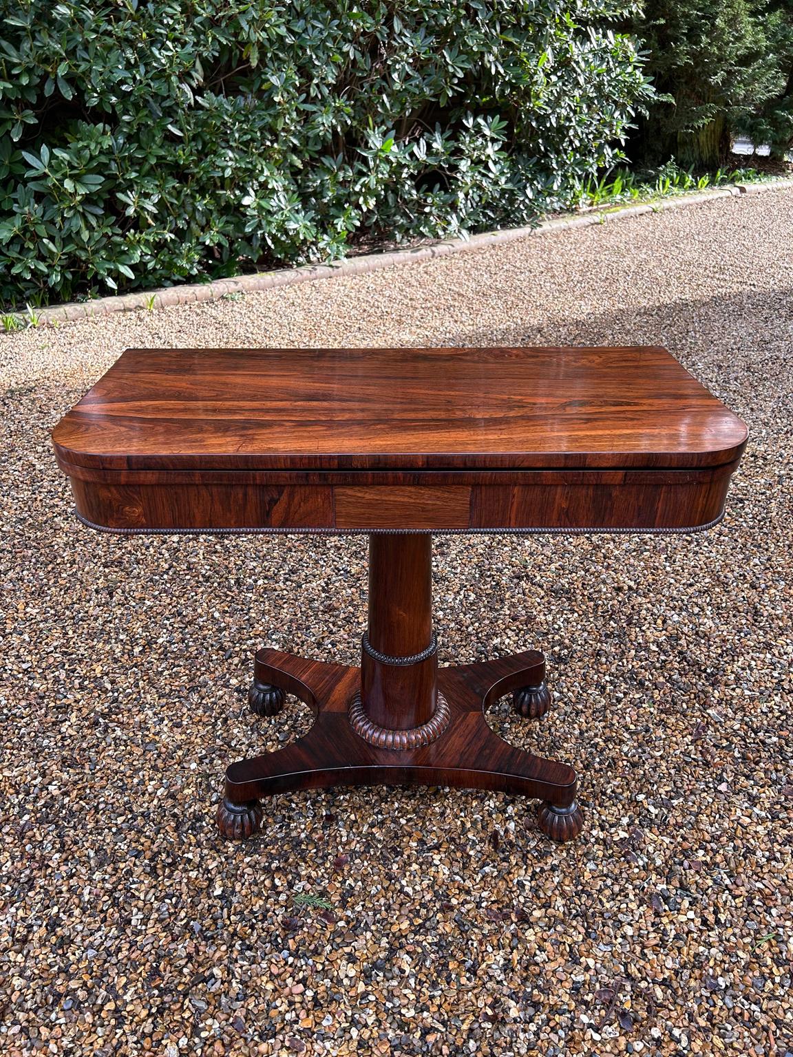 A very high quality William IV Rosewood Card Table with beautifully figured rosewood throughout. The top swivels 90′ degrees to open into a Card Table with a baize lined interior. The cylindrical turned rosewood column on lotus leaf collar,
