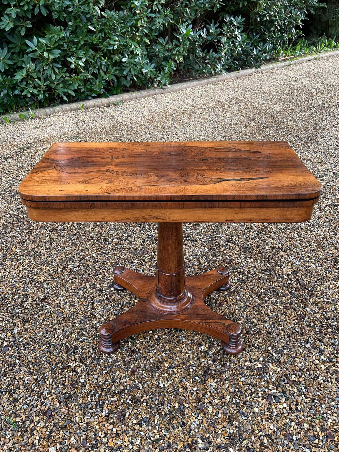A very high quality William IV Rosewood Card Table with beautifully figured rosewood throughout. The top swivels 90′ degrees to open into a Card Table with a original baize lined interior. The cylindrical turned rosewood column on lotus leaf collar,